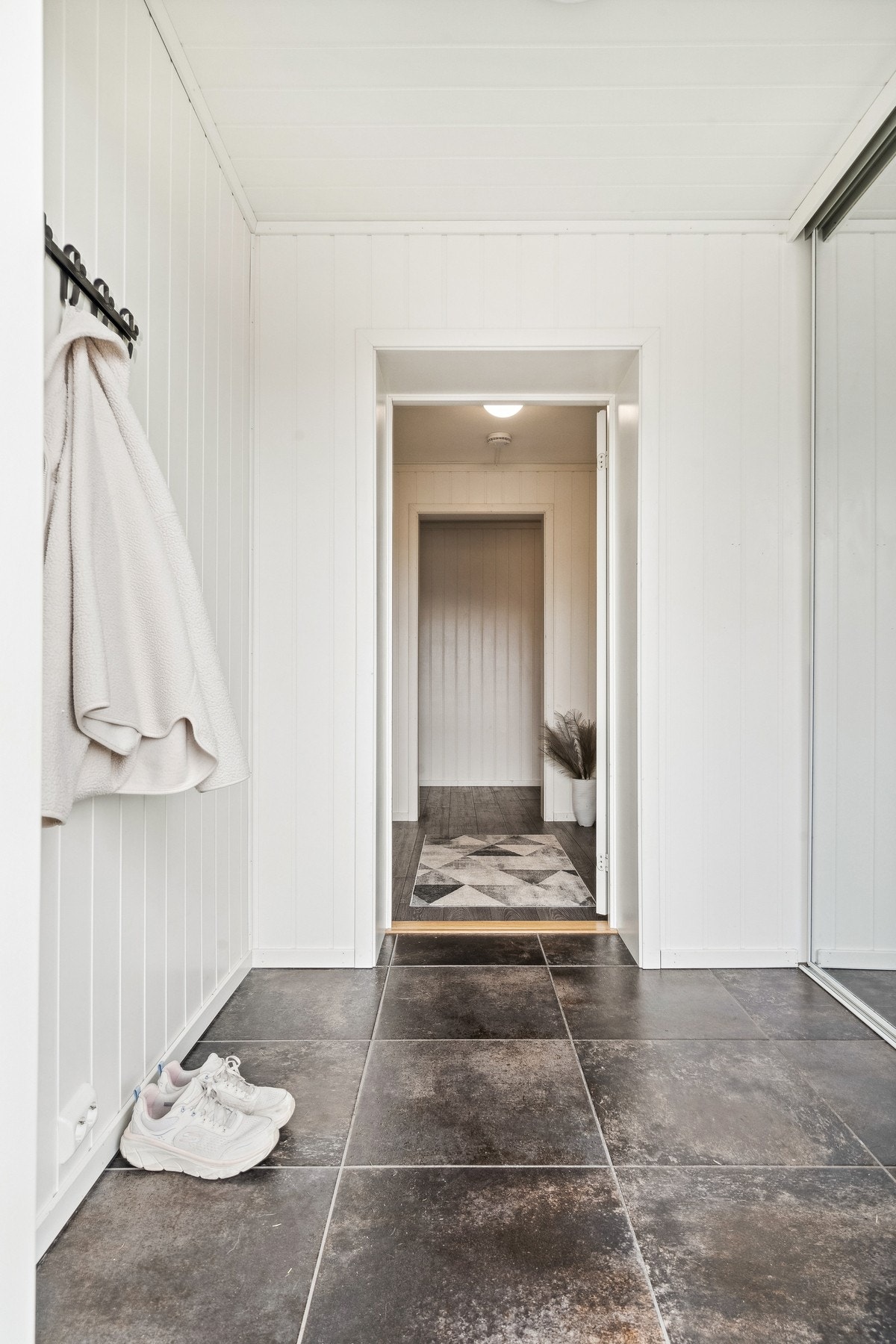 Velkommen inn! Entréen har flislagt gulv og skyvedørsgarderobe Galleribilde