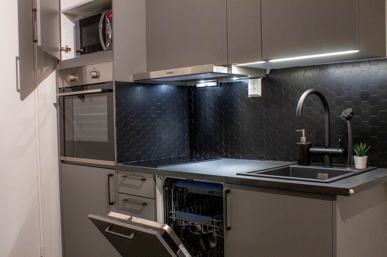 Kjøkkenet inneholder et lite kjøleskap, oppvaskmaskin, ovn og koketopp. Alt er integrert slik det fremgår av bildet. Galleribilde