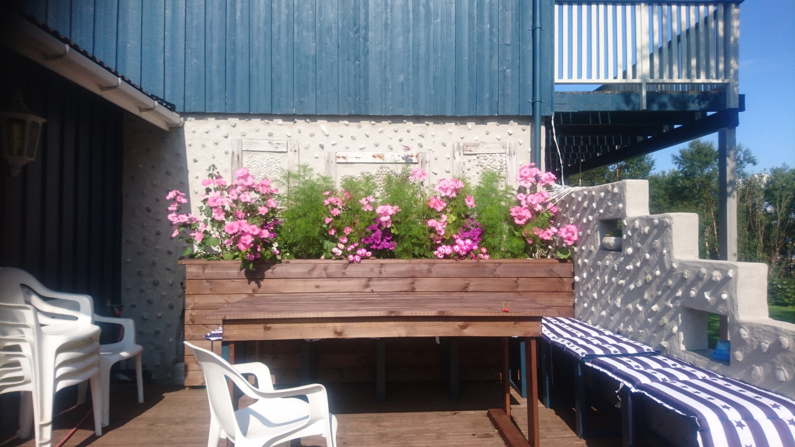 Terasseparti ved inngangsdør med fastmonterte benker og bord. Galleribilde