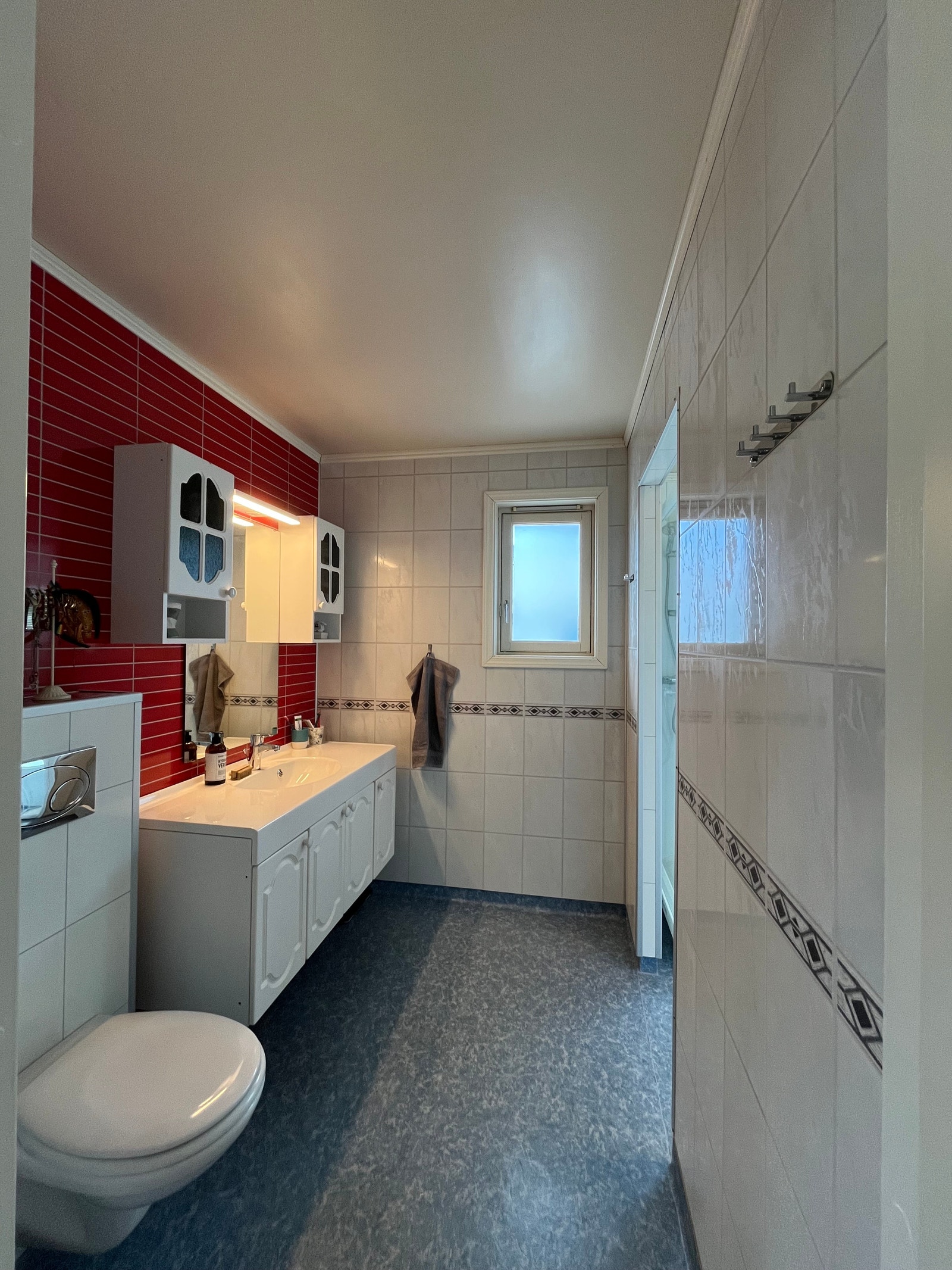 Bad sett fra baderomsdøra, her er det vegghengt toalett, servant, speil og skapplass. Inn til høyre står dusjkabinettet. Galleribilde