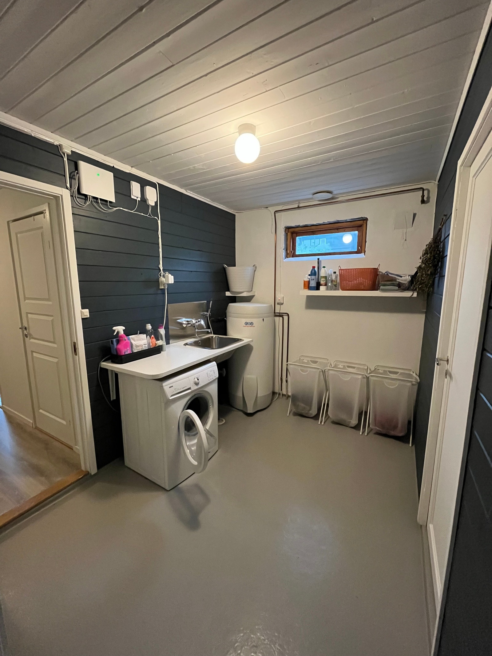 Vaskerommet sett fra inngangen til kjellerboden. På vaskerommet er det vaskemaskin, grovvask med dusjhode og varmtvannsbereder. Galleribilde