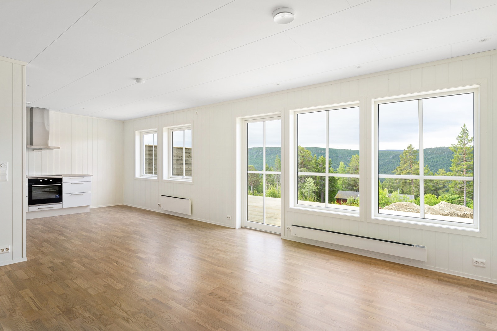 Store vinduer som slipper inn lys og naturen utenfor, platting foran hele kjøkken/stue-del Galleribilde