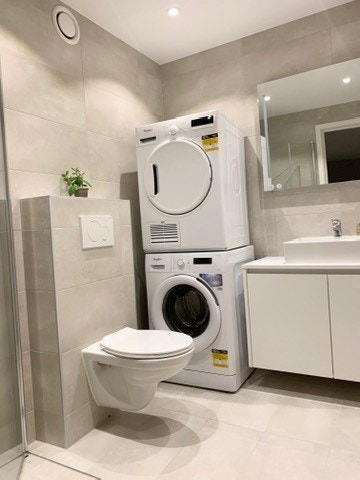 Bad med vaskemaskin og trommel. Varmekabler på gulv. Galleribilde