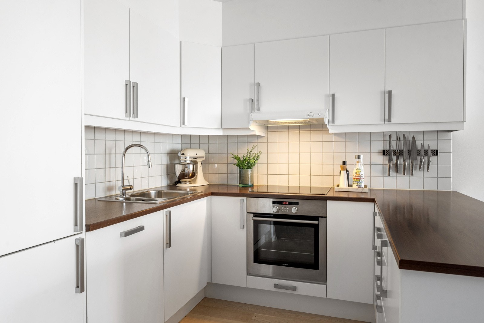 Kjøkkeninnredning fra 2008 med hvite slette fronter. Benkeplate av laminat med nedfelt oppvaskkum i rustfritt stål med ett-greps armatur og uttrekk. Galleribilde