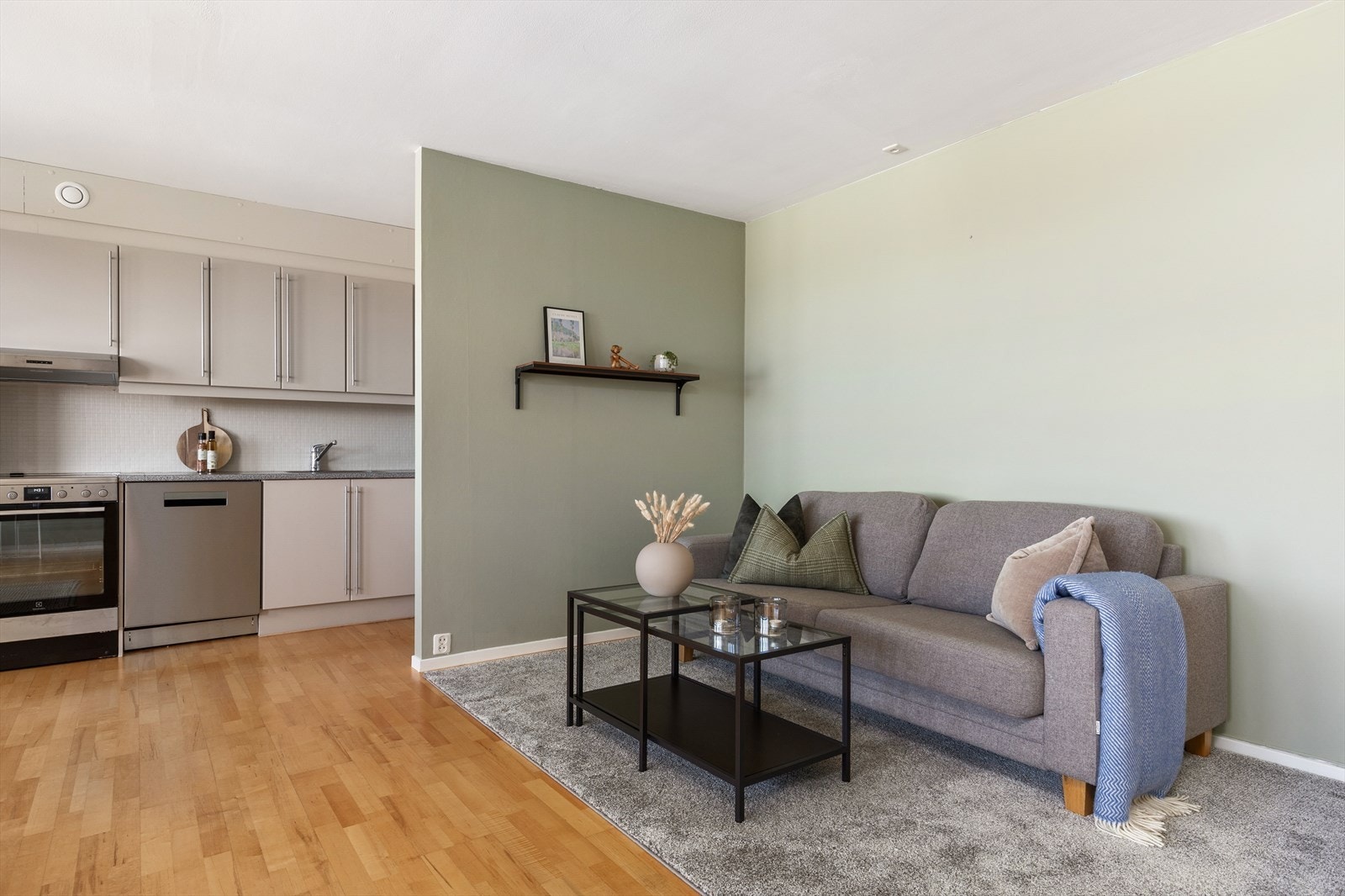 Stuens store og behagelige areal legger til rette for en stor og koselig sofagruppe og flere møbleringssoner. Stue og kjøkken er malt i de stilrene fargetonene "Laurbær" og "Modern Beige" i 2024. Galleribilde