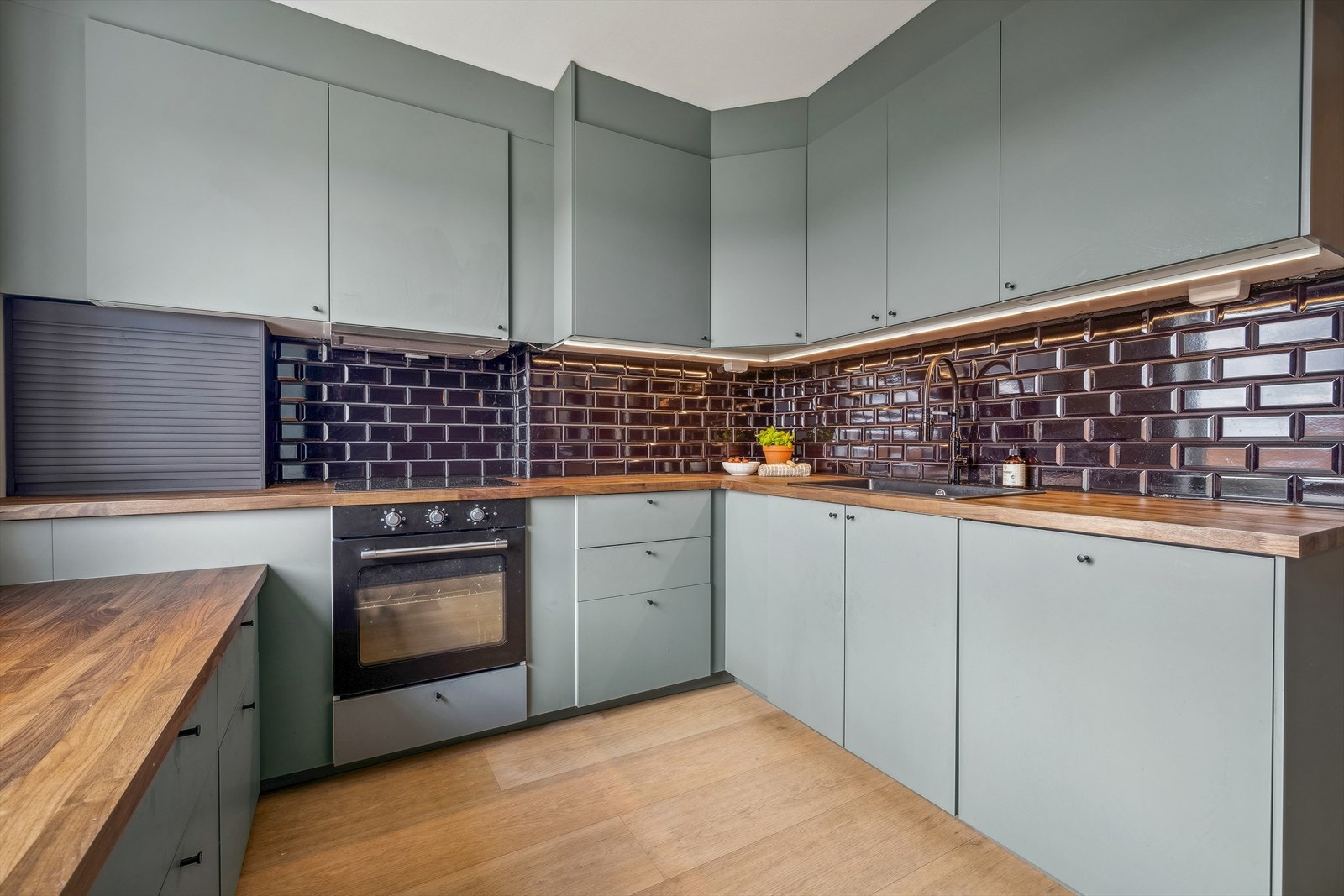 Kjøkkenninnredning med glatte fronter og takhøye overskap. Integrerte hvitevarer som platetopp, stekeovn, oppvaskmaskin og kjøl/fryseskap. Galleribilde