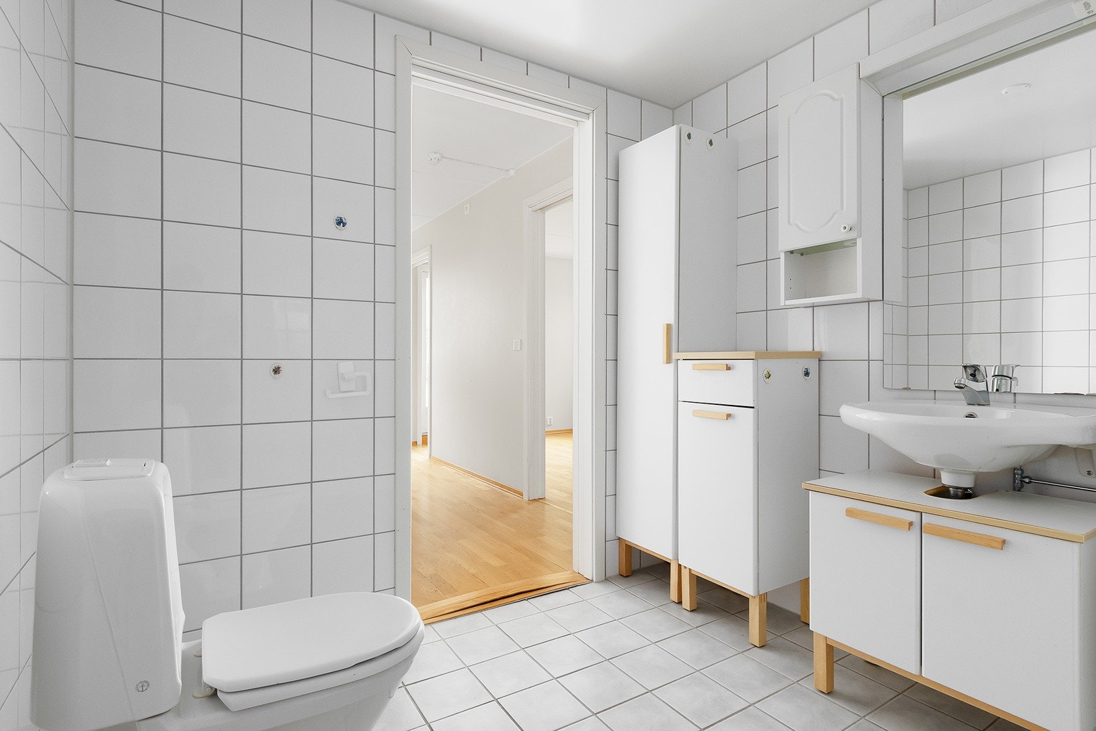 Baderomsinnredningen er bestående av servant med underskap, speil med overlys, veggskap, gulvmontert klosett, åpen dusjløsning og opplegg for vaskemaskin. Galleribilde