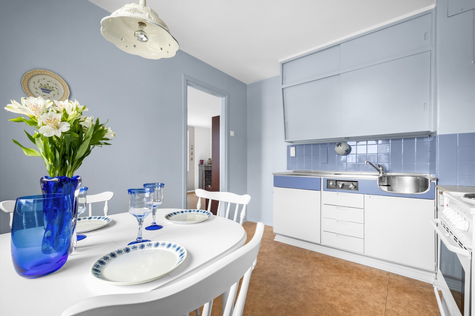 Kjøkkenet har plassbygde skap, karakteristiske skrå overskap med skyvedører, en vaskebenk med heldekkende benkebeslag og benkeplate i laminat. Galleribilde