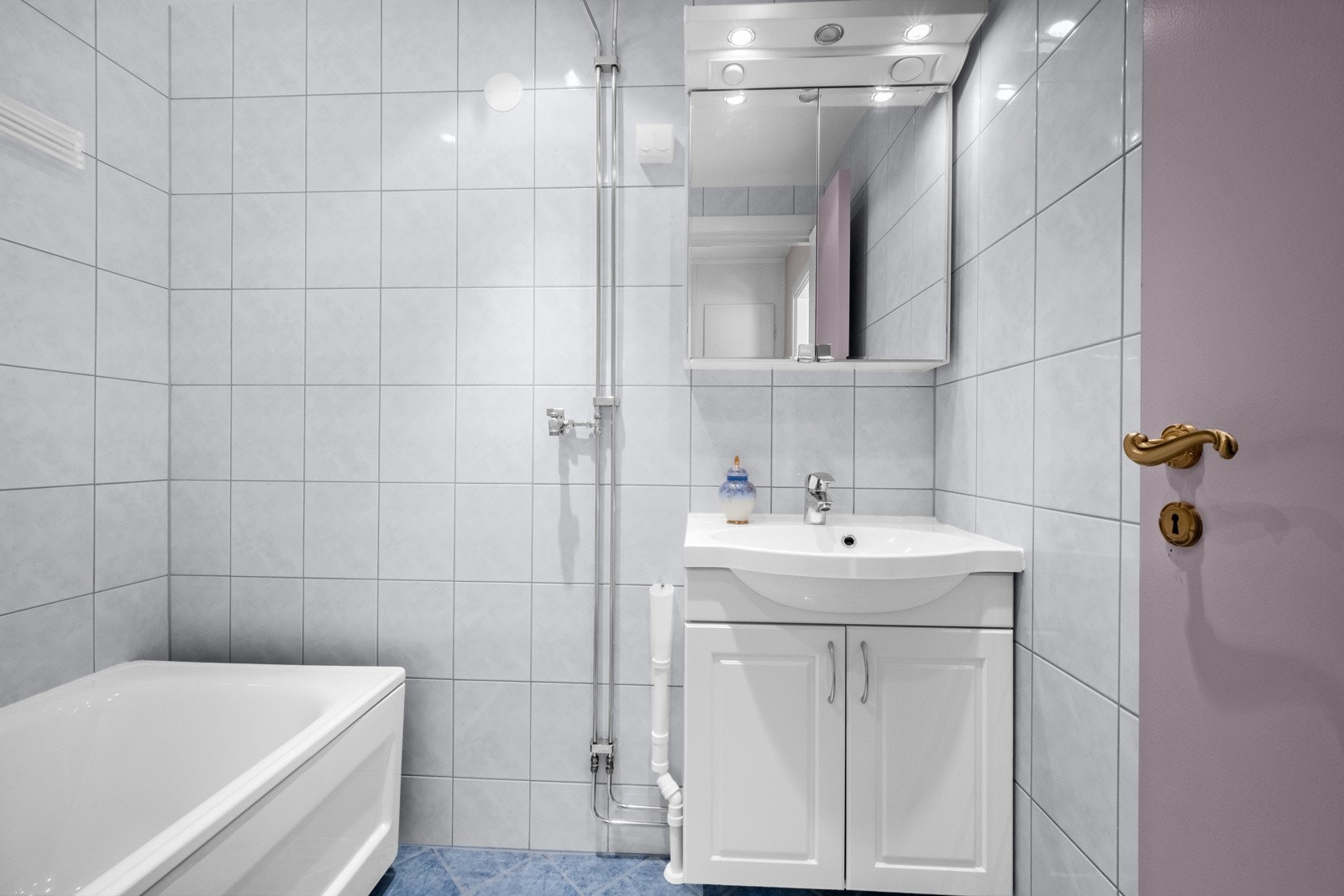 Den øvrige innredningen består av en heldekkende servant på hvitt skap og et speilskap med overlys. Det er gulvvarme og opplegg for vaskemaskin. Galleribilde