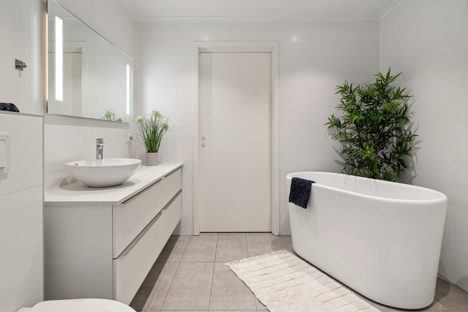 Delikat baderom med gulvvarme. Innredet med dusjsone, badekar, servant med underskap og vegghengt toalett. Inngang til praktisk vaskerom. Galleribilde