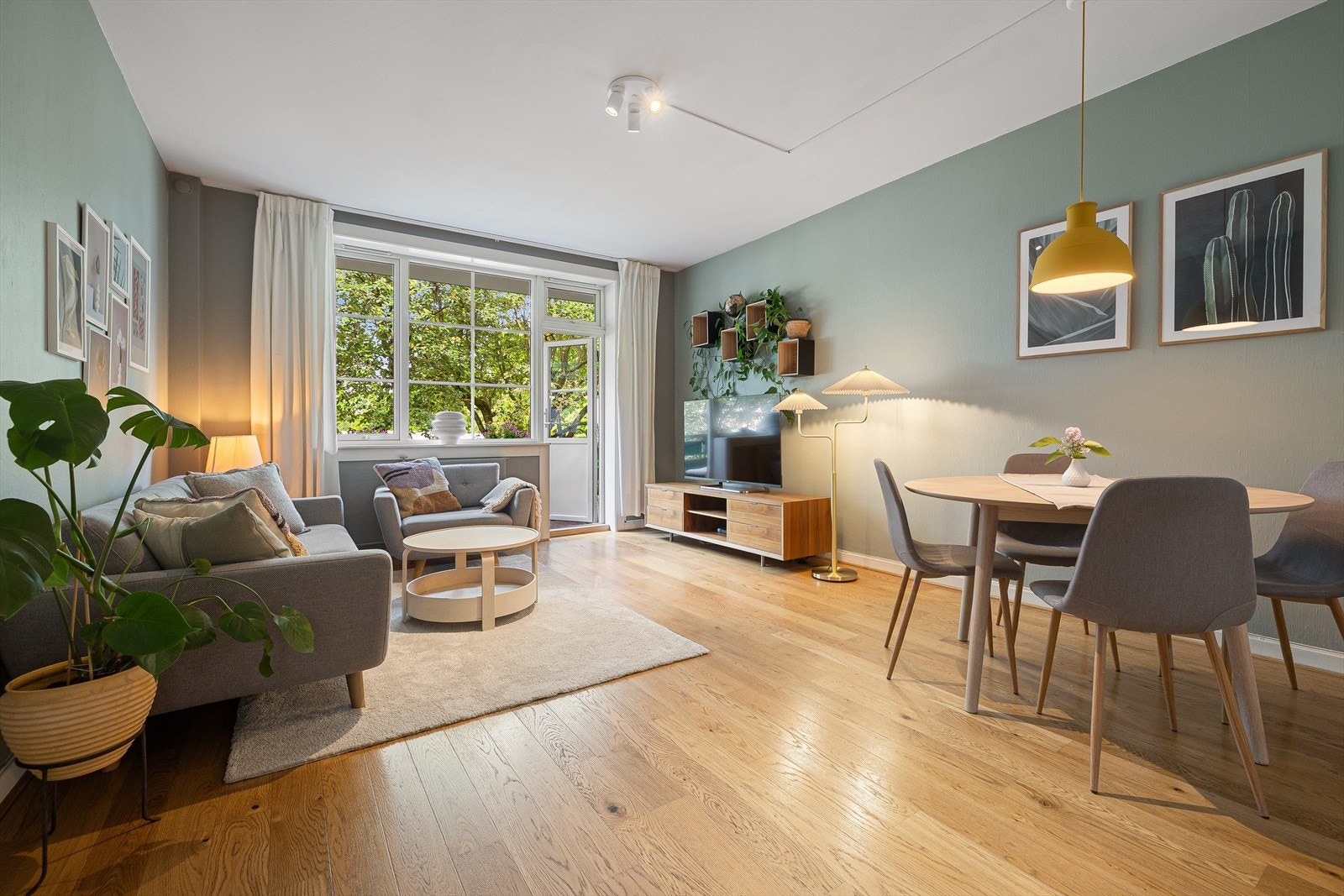 Stuen i leiligheten er romslig og flott opplyst med store vindusflater som gir rikelig med naturlig lys, og skaper en god atmosfære Galleribilde