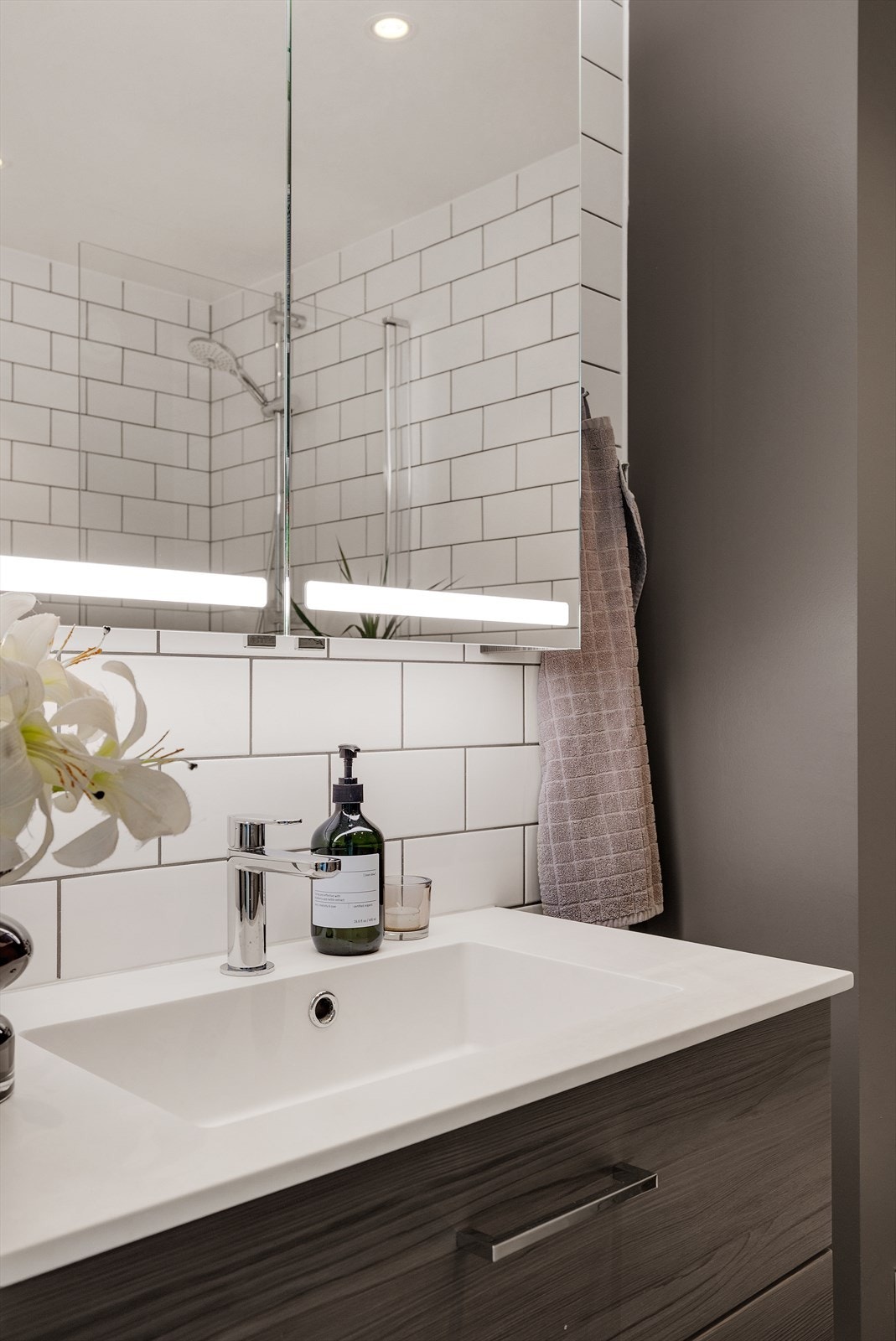 Badet er innredet med servantinnredning, heldekkende servant med ett-greps armatur, speilskap med lys og stikkontakt på vegg, badekar og toalett. Galleribilde