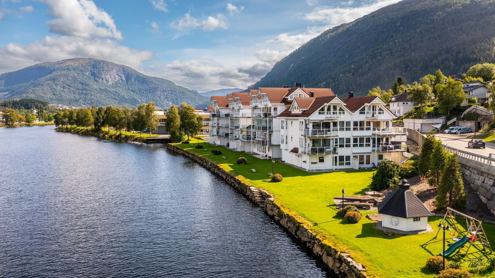 Fellesarealet er opparbeidet med grillhytte, lekestativ og benker ved elvekanten. Galleribilde