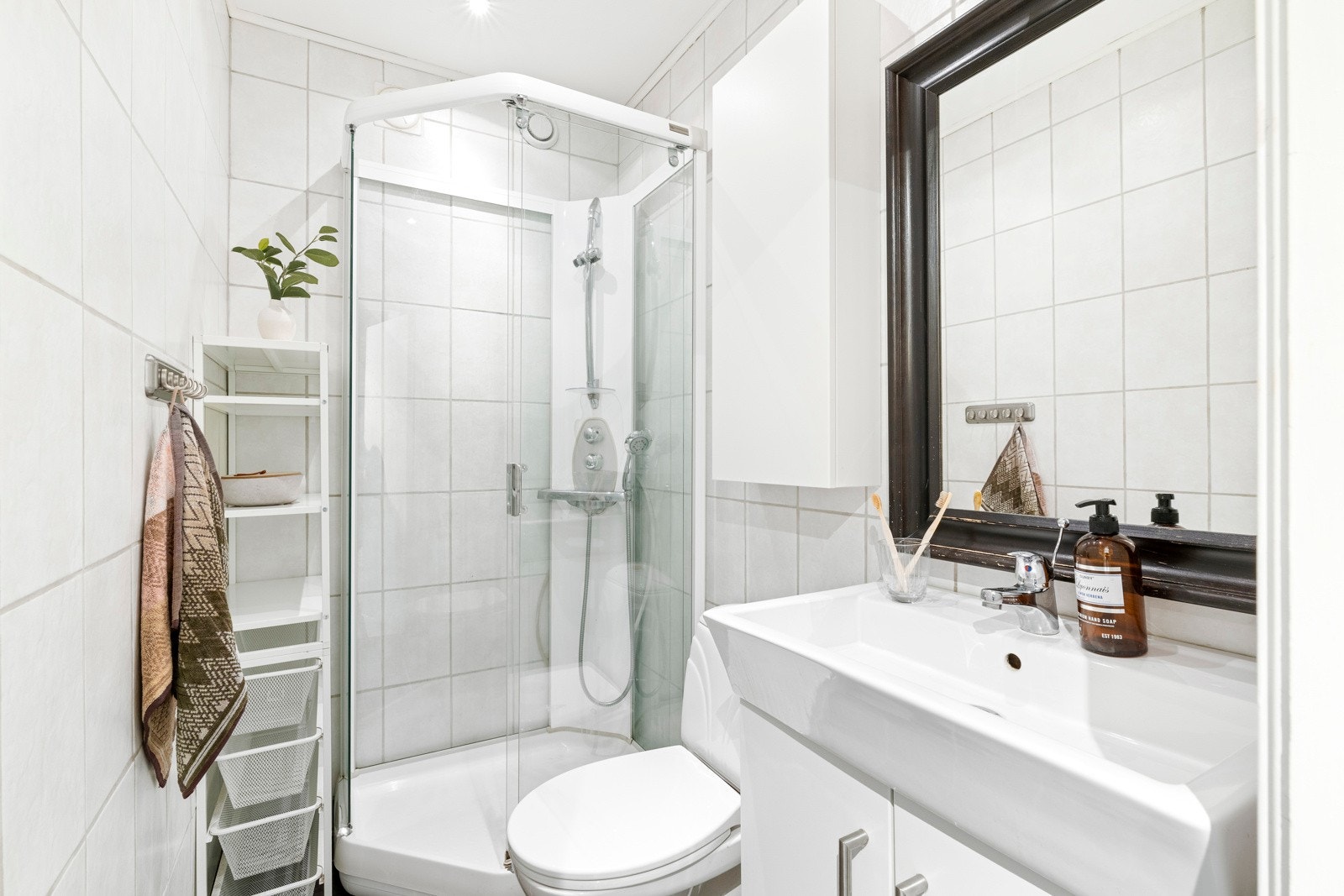 Badet er innredet med hvit baderomsinnredning med heldekkende servant og tilhørende vegghengt skap. Galleribilde