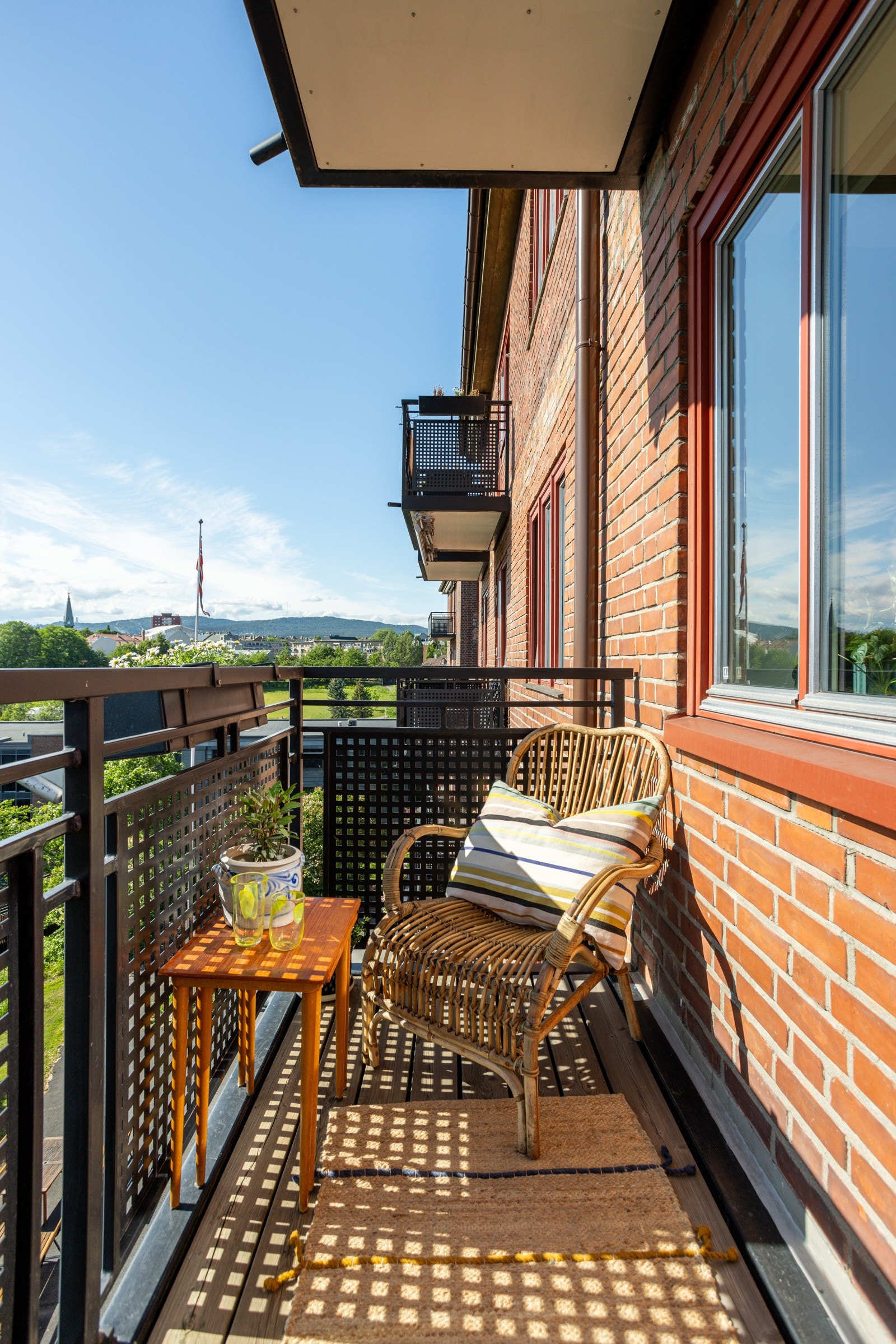Balkongen har terrassebord på gulv, rekkverk av stålkonstruksjoner og plass til hyggelig sittegruppe. Galleribilde