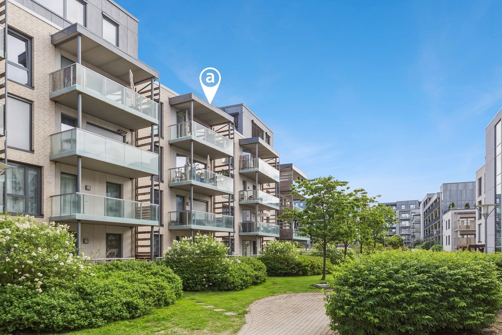 Fellestomten er pent opparbeidet med asfalterte internveier, steinbelagte områder, gressplen og frodig beplantning. Galleribilde