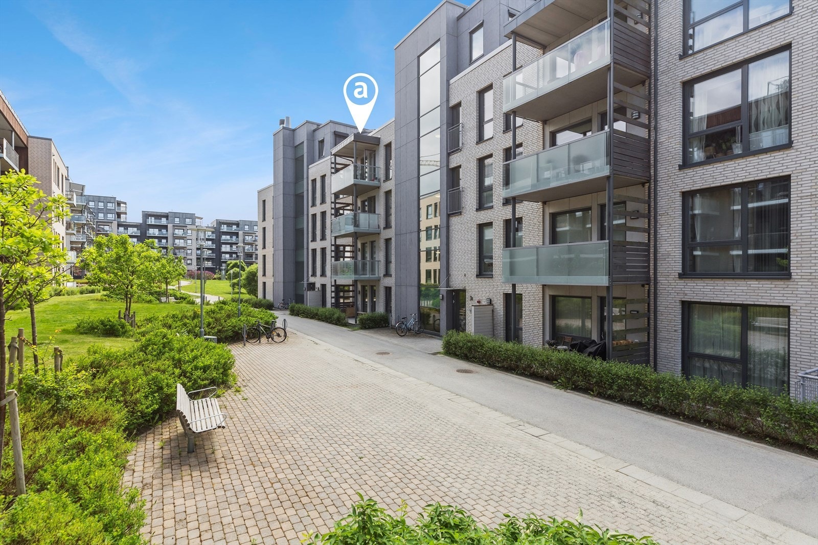 Det er sittebenker og sykkelstativer til felles anvendelse ved inngangen. Galleribilde