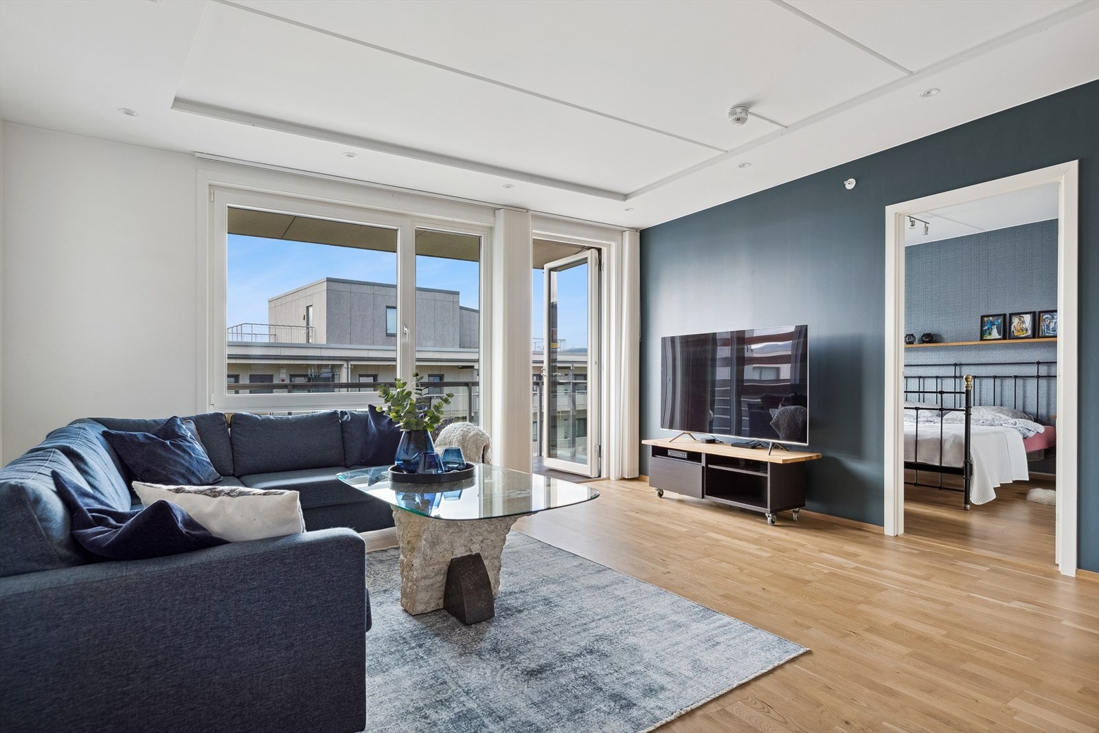 Allrommet som utgjør stue og kjøkken får rikelig med naturlig lys fra store vinduer i hver ende av rommet. Galleribilde