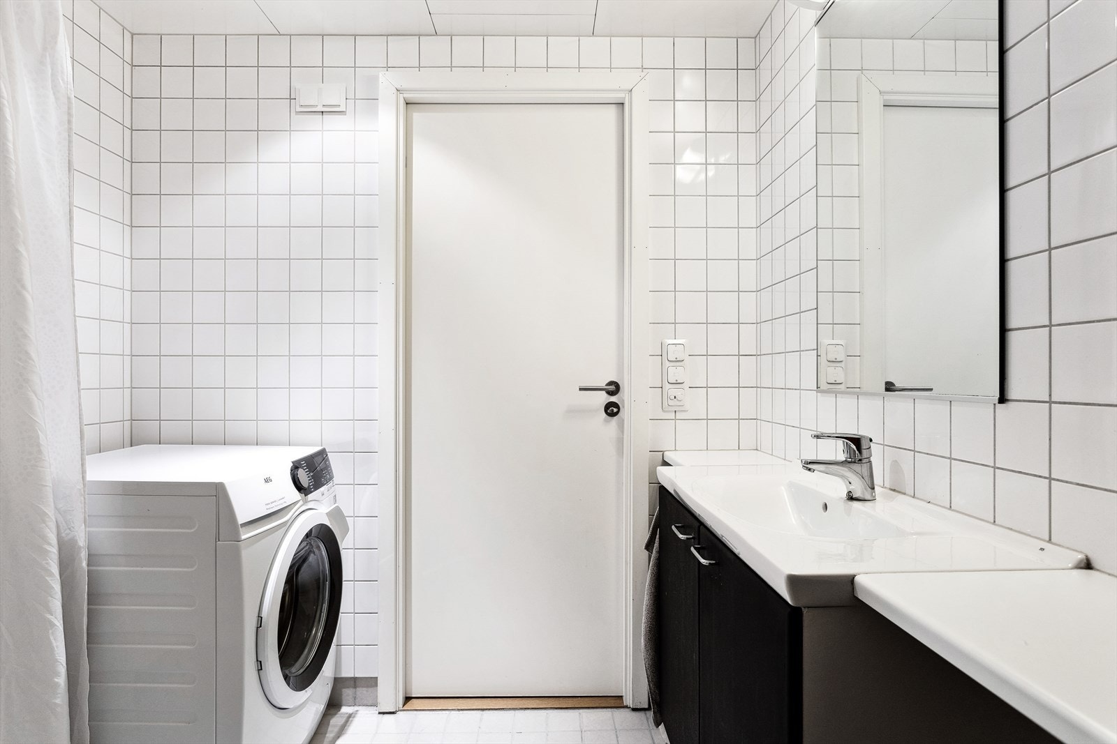 Badet er fra byggeår med varmekabler, flislagte flater, dusjhjørne, veggmontert servantinnredning og toalett samt opplegg for vaskemaskin. Galleribilde