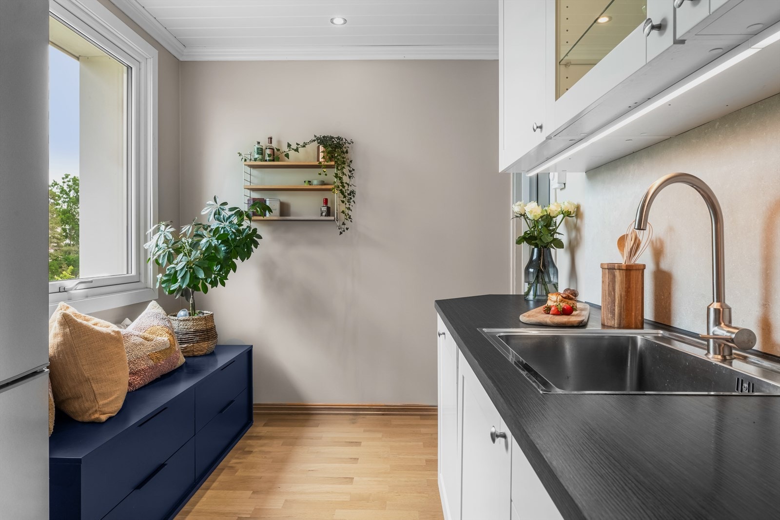 Innredningen har fabrikklakkerte, profilerte fronter og består av benkeplate i laminat med kjøkkenkran og nedfelt oppvaskkum. Galleribilde