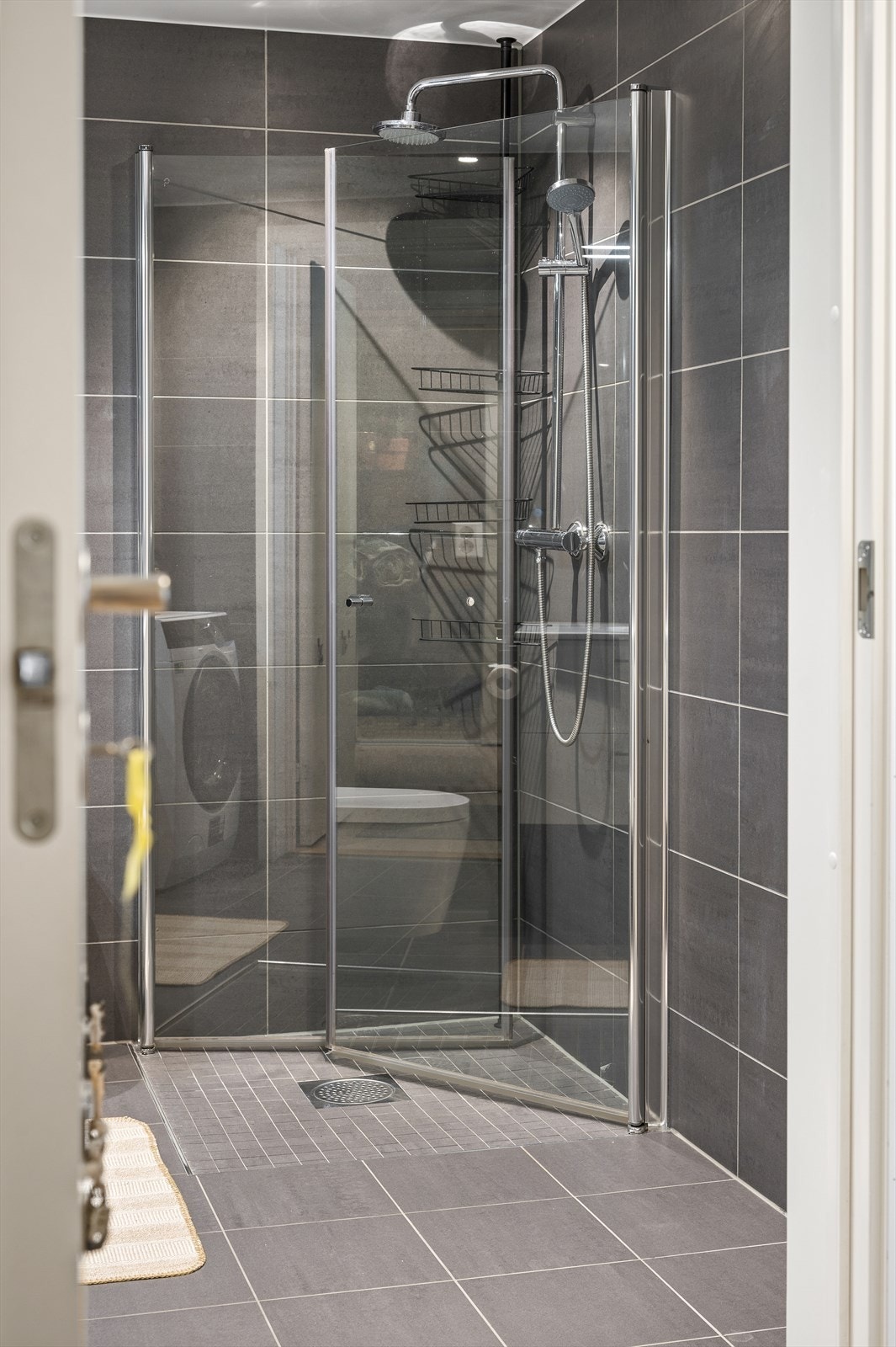 Badet er utstyrt med vegghengt toalett, dusjhjørne med innfellbare glassdører og rainshower Galleribilde