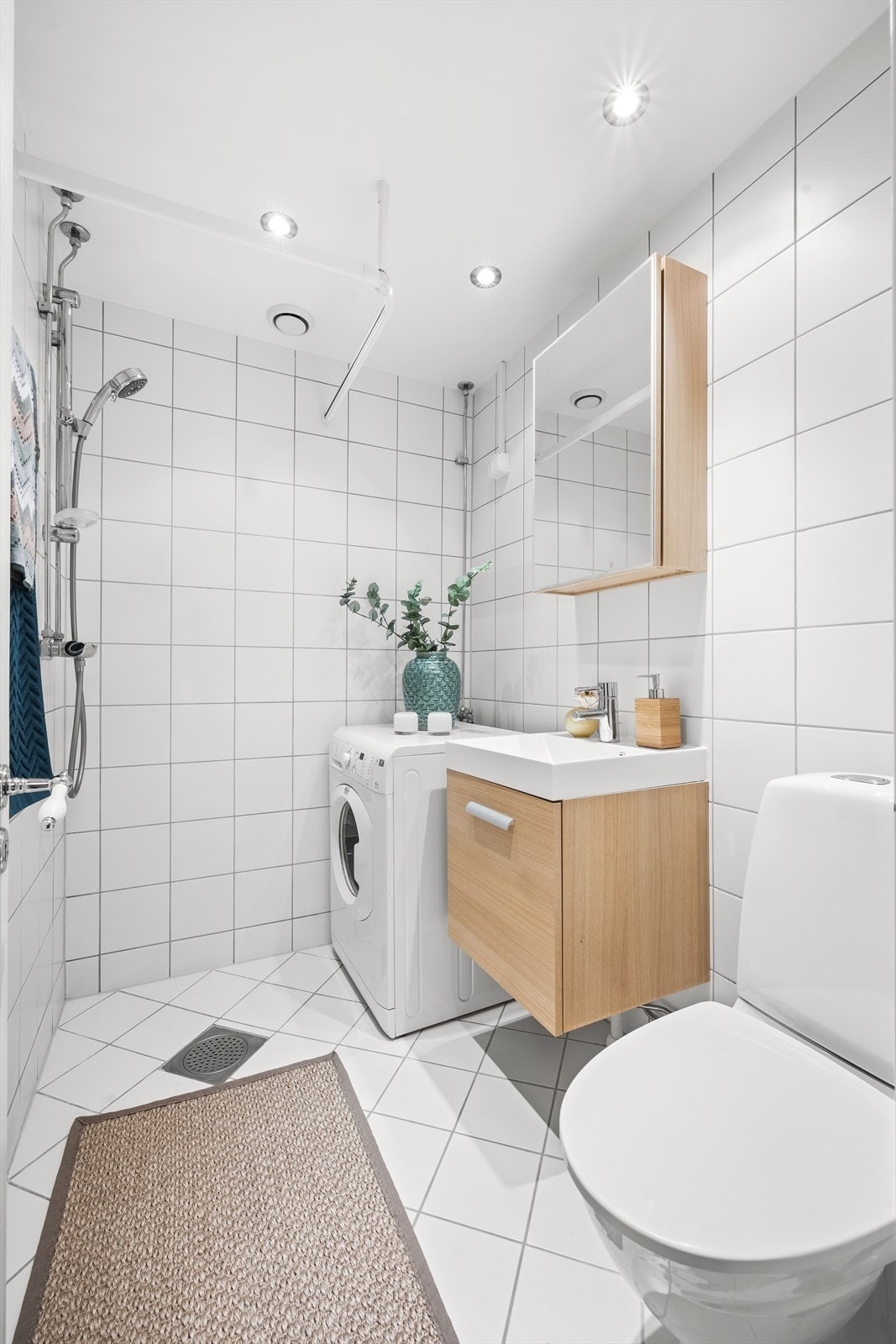 Innredningen på badet består av vegghengt servantskap med ovenpåliggende servant. Over servanten er det et praktisk speilskap. Gulvstående toalett, dusjhjørne og vaskemaskin. Galleribilde