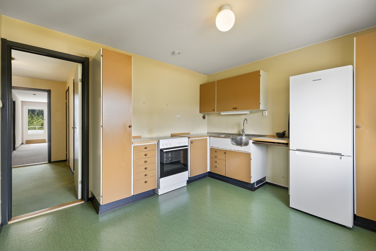 Kjøkkeninnredningen med laminert benkeplate med nedfelt stål oppvaskkum med ett-greps blandebatteri. Det er opplegg for komfyr. Galleribilde