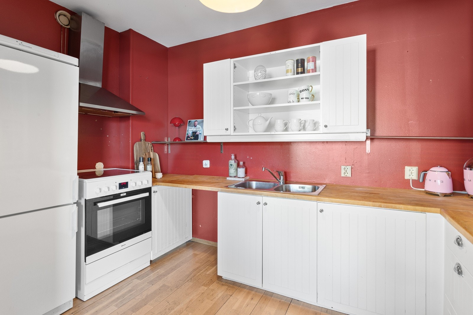 Kjøkkenet har rødmalte vegger, eldre innredning og benkeplate i heltre. Galleribilde