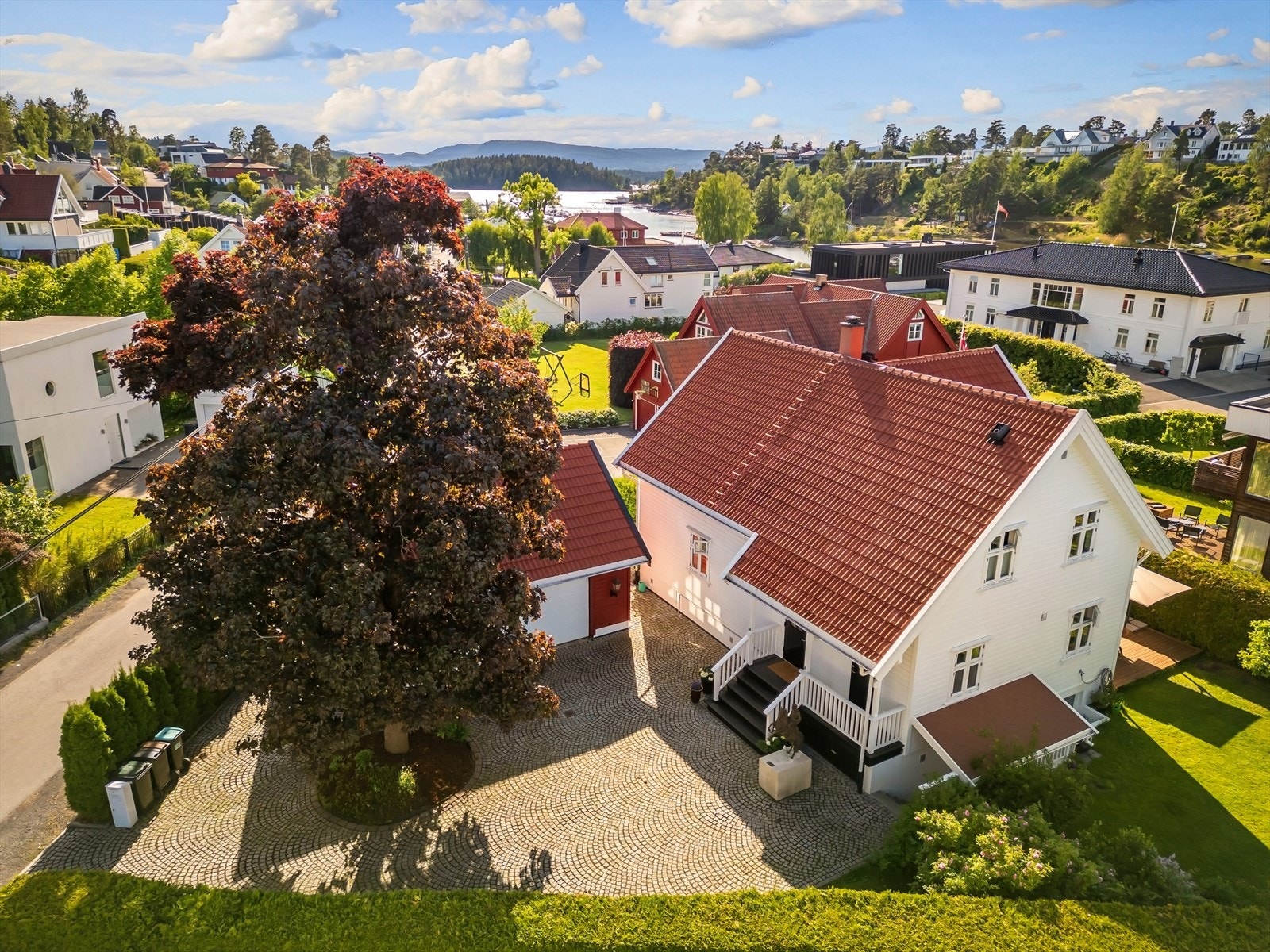 Pent opparbeidet eiendom som har innkjøring og gårdsplass med brosten i viftemønster og et flott tuntre på gårdsplassen Galleribilde