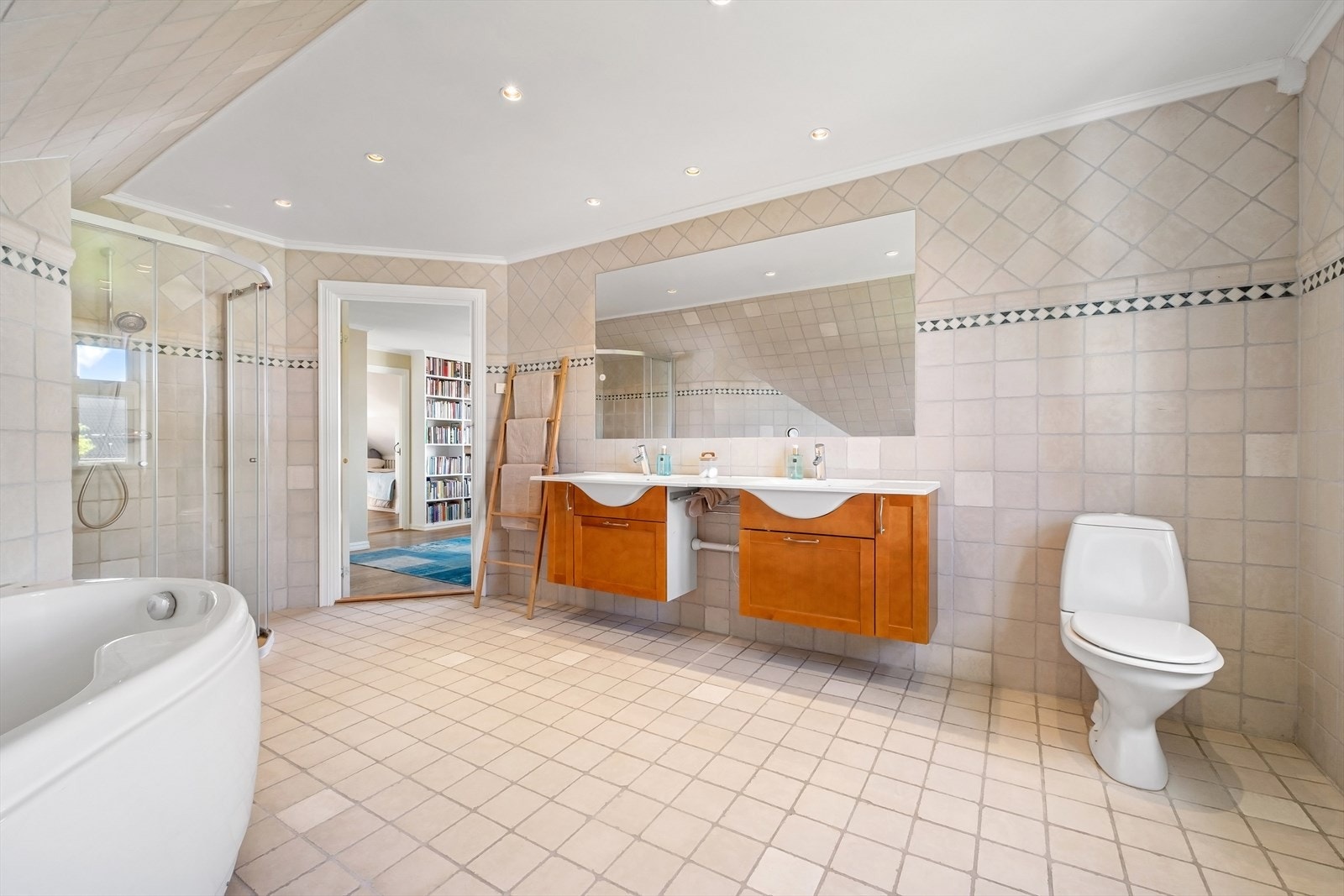 Videre er det badekar og dusjvegger i hjørnet - Flislagt bad med downlights og vannbåren gulvvarme Galleribilde