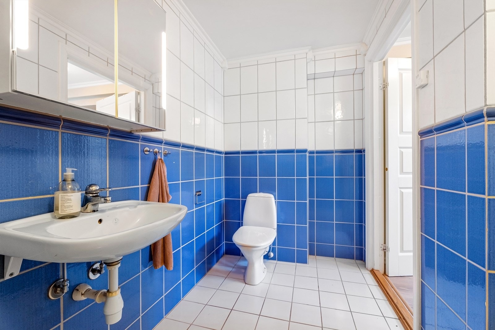 Flislagt bad med servant, speilskap, gulvmontert toalett, dusjvegger i hjørnet og opplegg for vaskemaskin og varmtvannsbereder på 200 liter fra 2001 Galleribilde