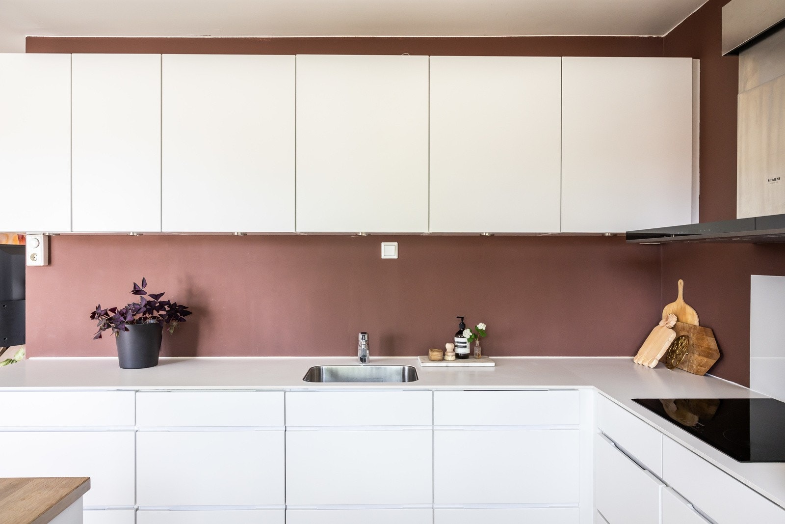 Innredning fra Kvik med hvite profilerte fronter, integrerte hvitevarer fra Siemens, som mikro- og stekeovn i høyskap, koketopp, kjøleskap/fryser og oppvaskmaskin. Galleribilde