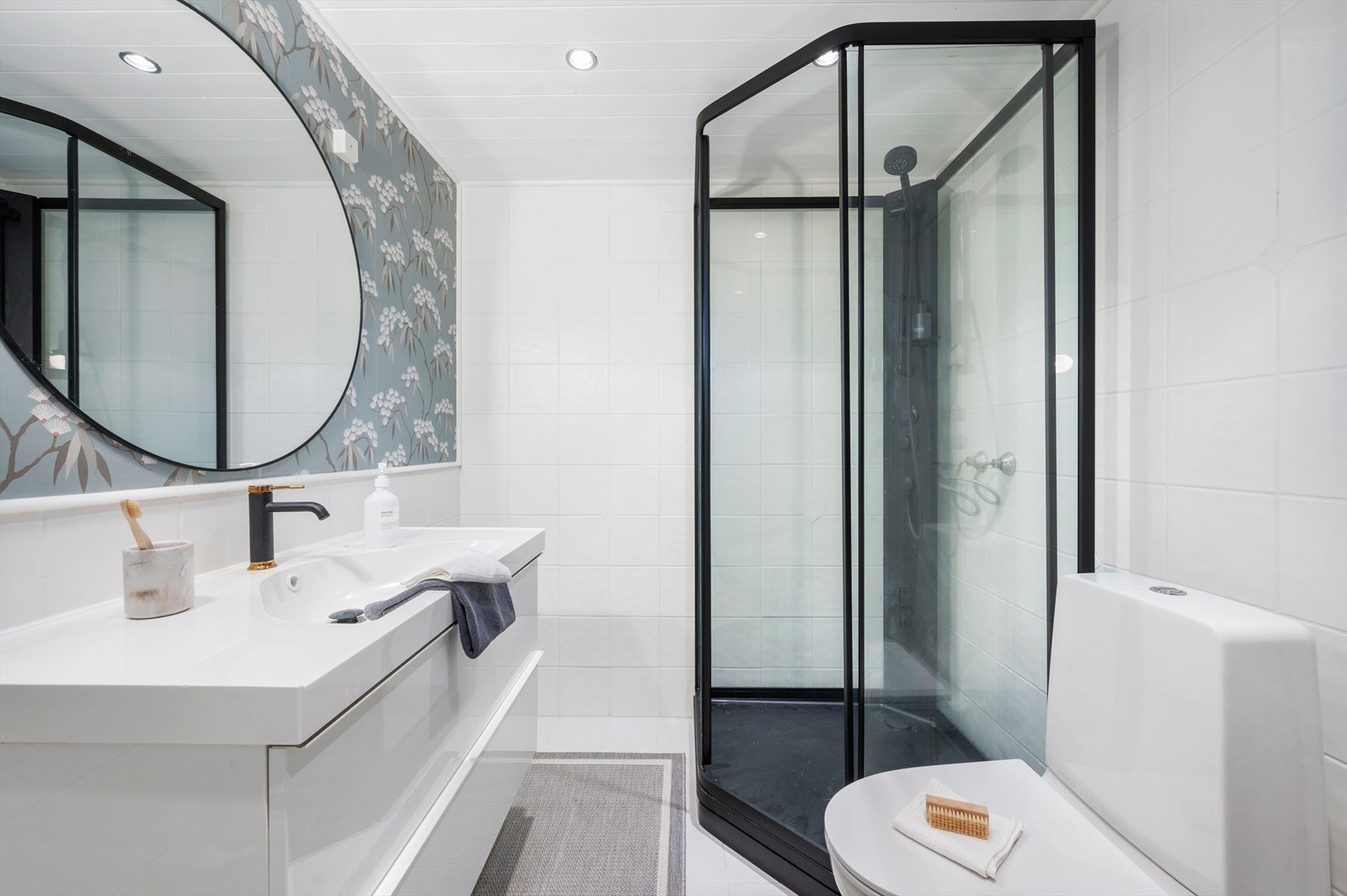 Badet inneholder toalett, helstøpt servant, skuffer under servant med slette fronter og dusjkabinett. Galleribilde