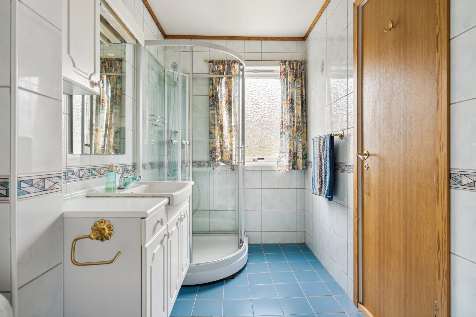 Flislagt bad i hovedplan utstyrt med dusjkabinett, servant og tilhørende baderomsinnredning. Galleribilde