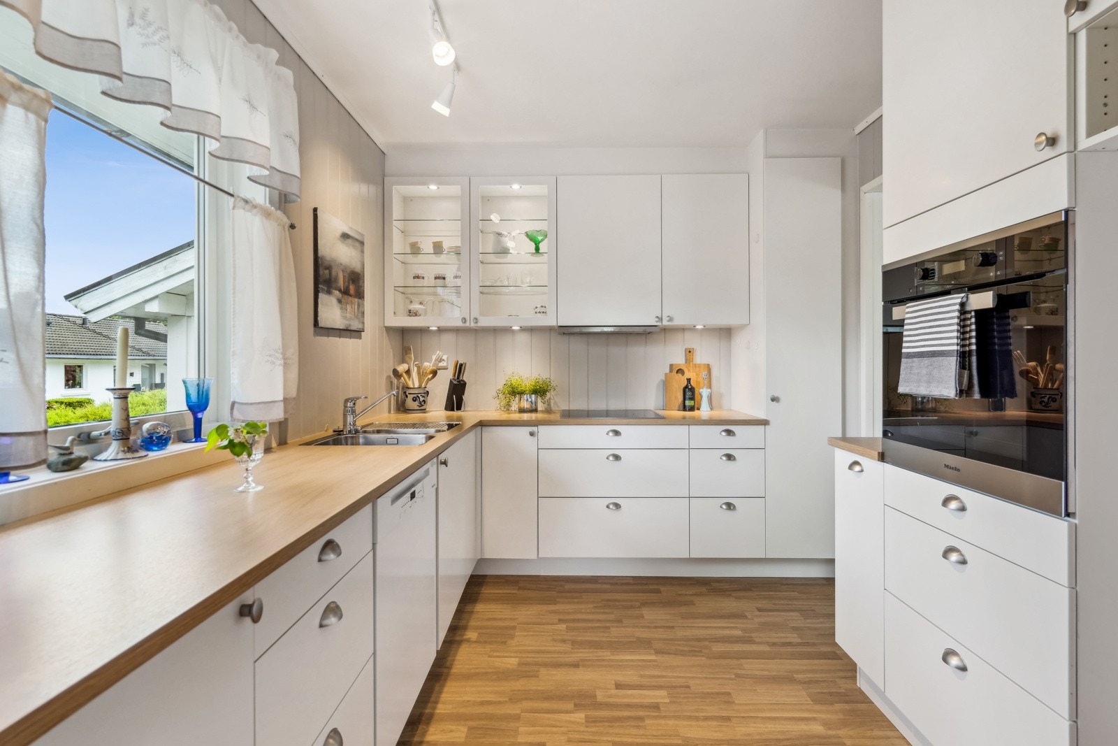 Delikat HTH-kjøkken utstyrt med flere integrerte hvitevarer - mellom annet stekeovn, oppvaskmaskin og platetopp. Galleribilde