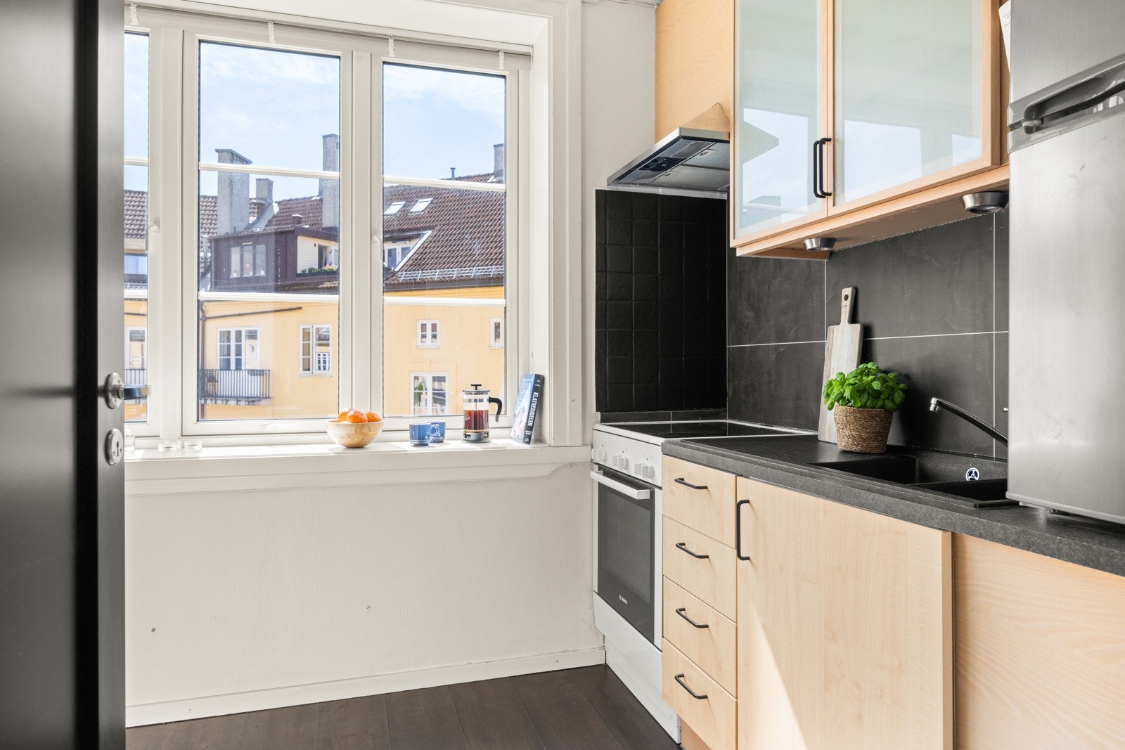 Kjøkkenet er utstyrt med frittstående komfyr med keramisk platetopp, frittstående kjøleskap med frysedel over benk, samt varmtvannsbereder plassert under benk. Galleribilde