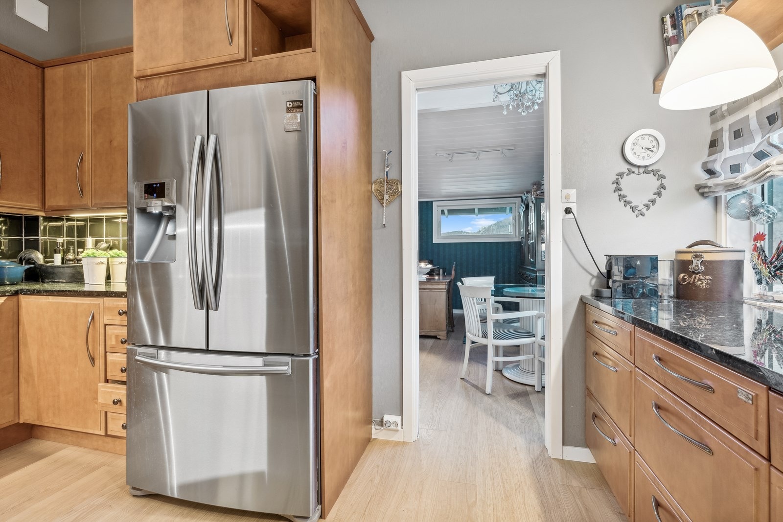 Kjøkkenet er separat, har profilerte fronter i heltre, benkeplate i stein, dobbel stålvask med benkebeslag og fliser på vegg over benk Galleribilde