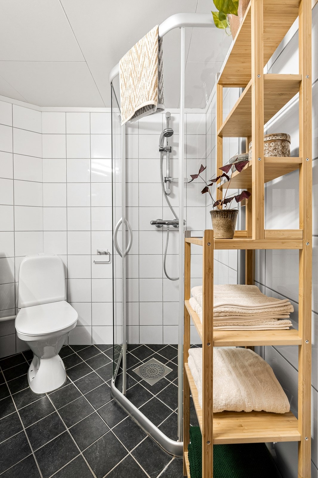 Badet er innredet med dusjhjørne med skyvedør, gulvstående toalett, servant med underskap og speil med lys. Det er opplegg for vaskemaskin, og vaskemaskinen medfølger. Galleribilde