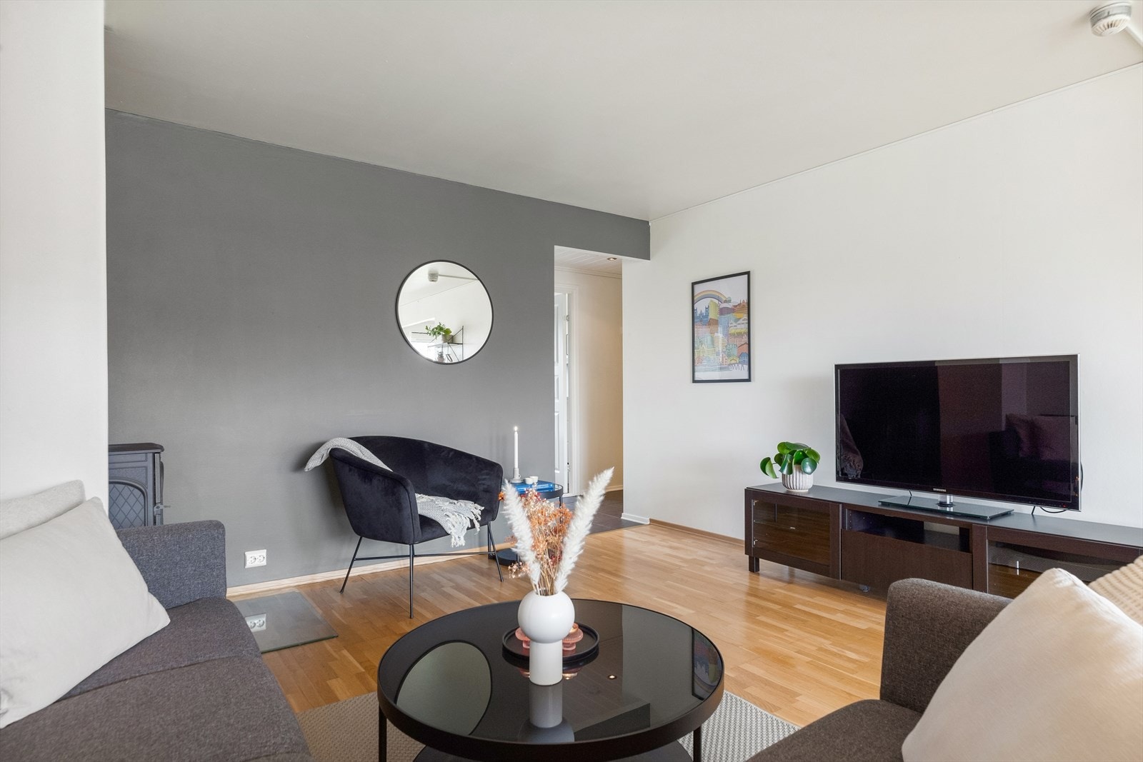 Stuen er holdt i en stilren kombinasjon med grå- og hvitmalte vegger og gyllent parkettgulv. Galleribilde