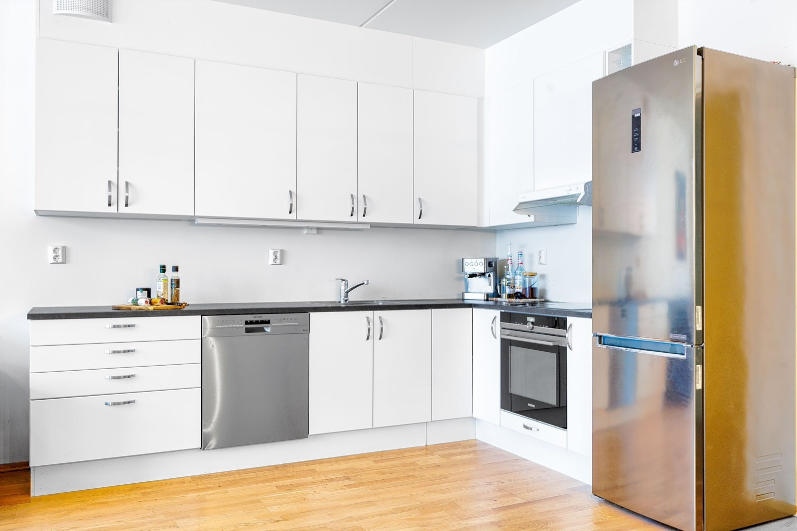 Pent kjøkken innredet med hvite, slette fronter og benkeplate av laminat Galleribilde