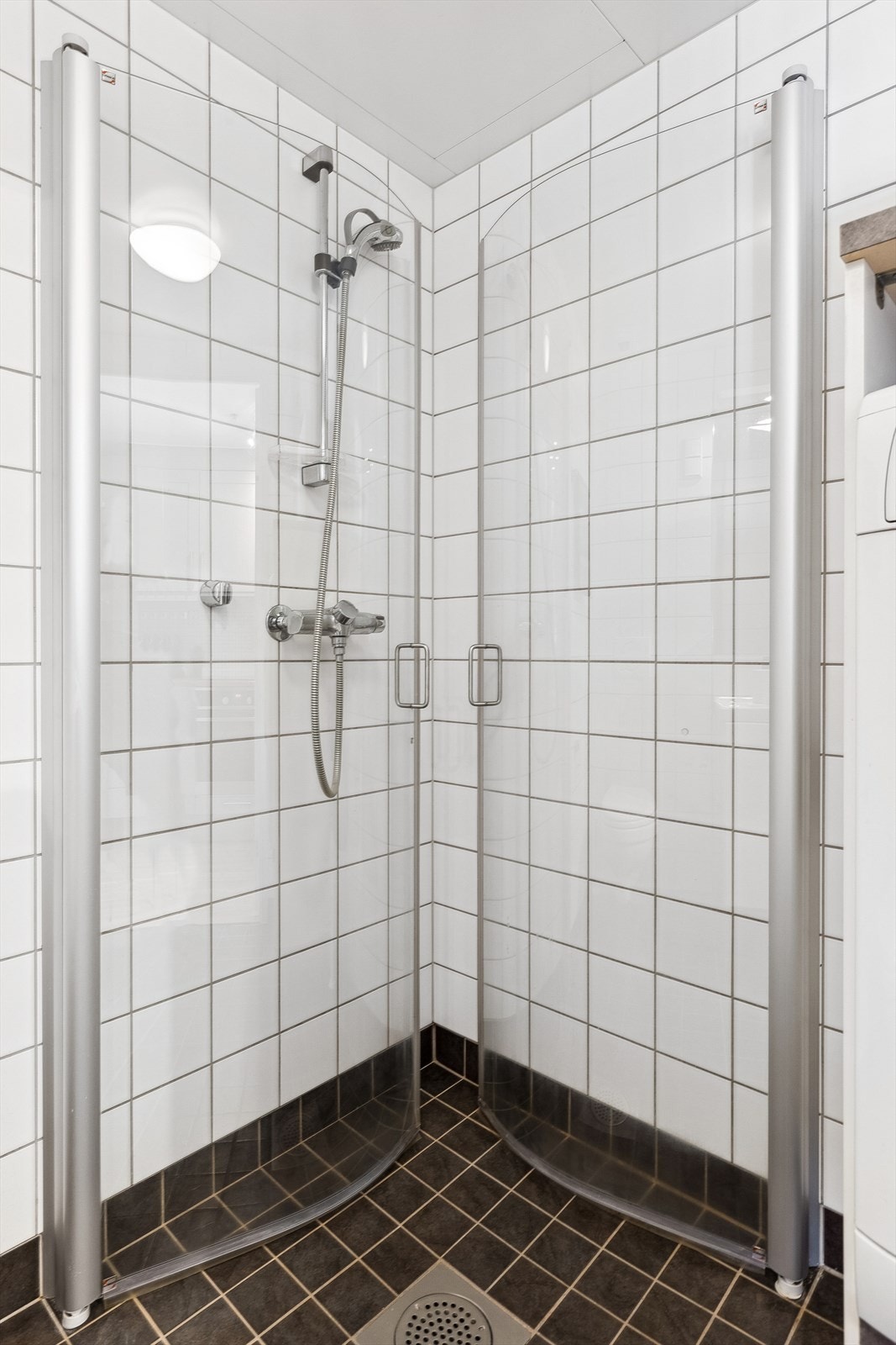 Badet har dusjhjørne med svingbare dører og opplegg til vaskemaskin. Galleribilde