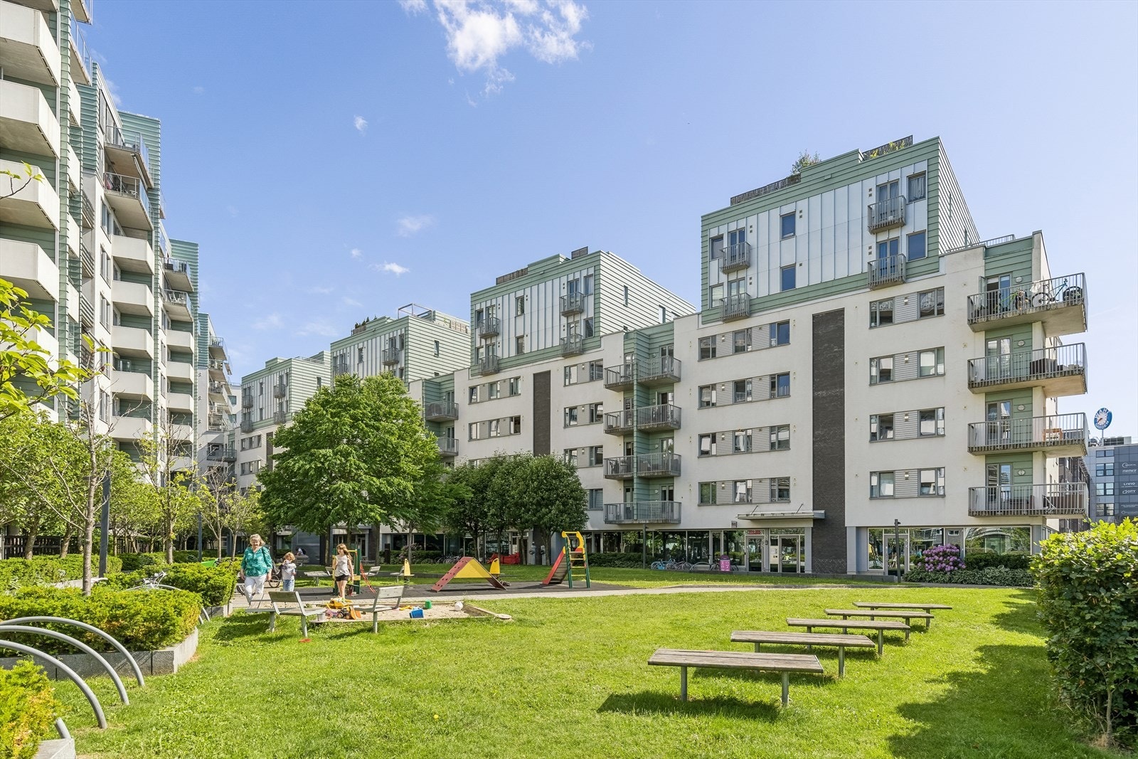 Pent opparbeidet gårdsrom med beplantning, gangveier, lekearealer og sitteplasser. Galleribilde