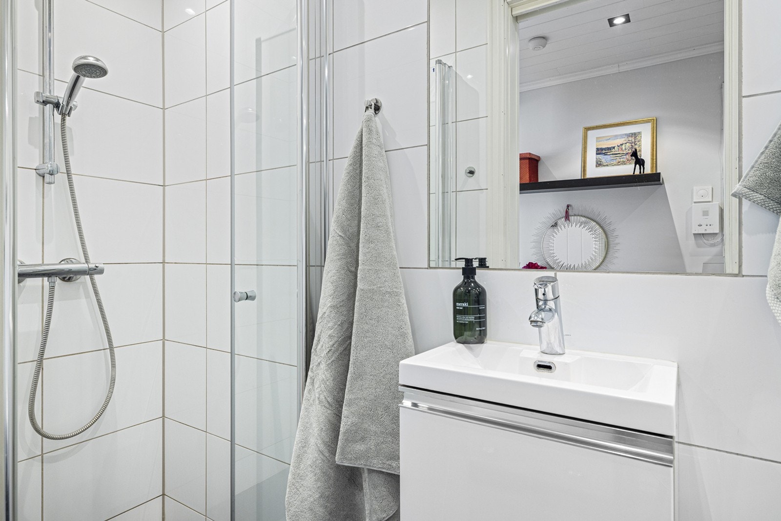 Badet er moderne og praktisk med dusjnisje med innfellbare glassvegger, vegghengt toalett, speilskap og servant med skuffeløsning. Galleribilde