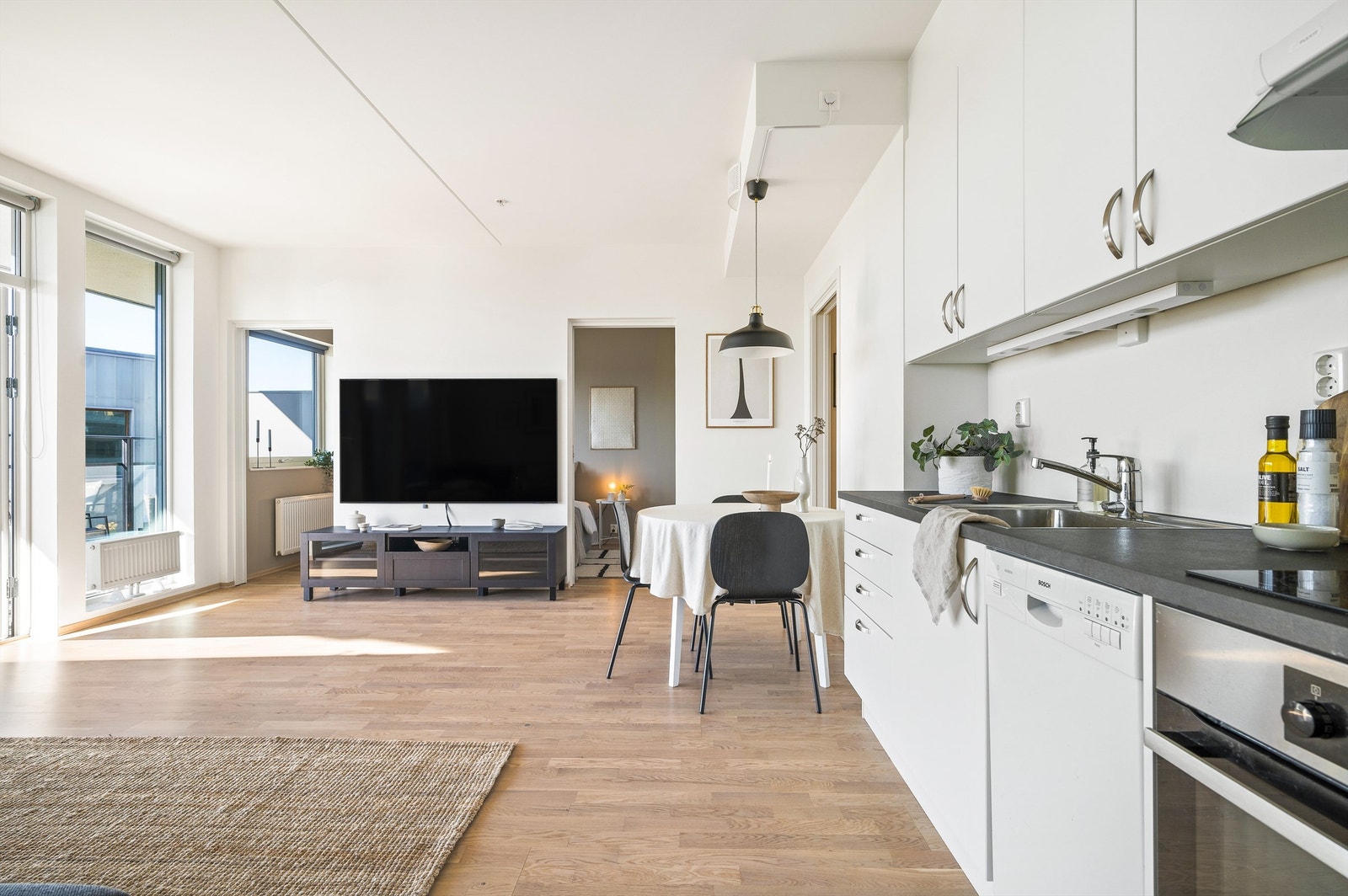 Tidløst og moderne kjøkken med glatte fronter i matt hvit utførelse og benkeplate av laminat. Galleribilde