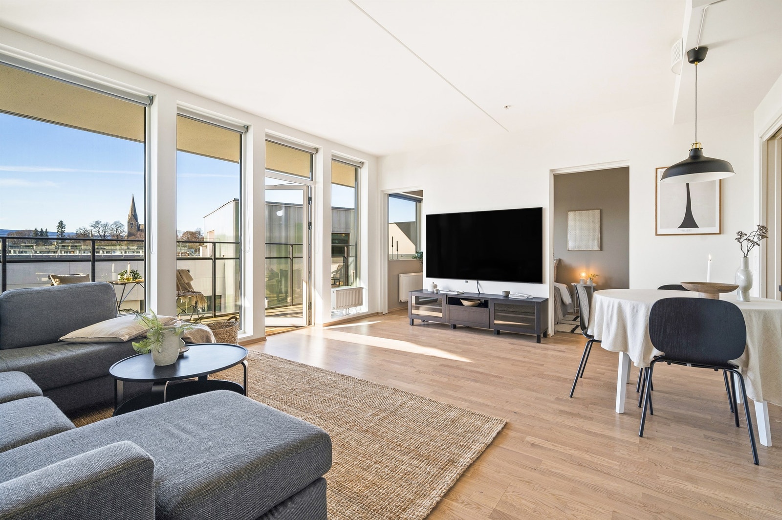 Lys, romslig stue med åpen og sosial stue- og kjøkkenløsning. Store vinduer fra gulv til tak sørger for rikelig med dagslys. Galleribilde