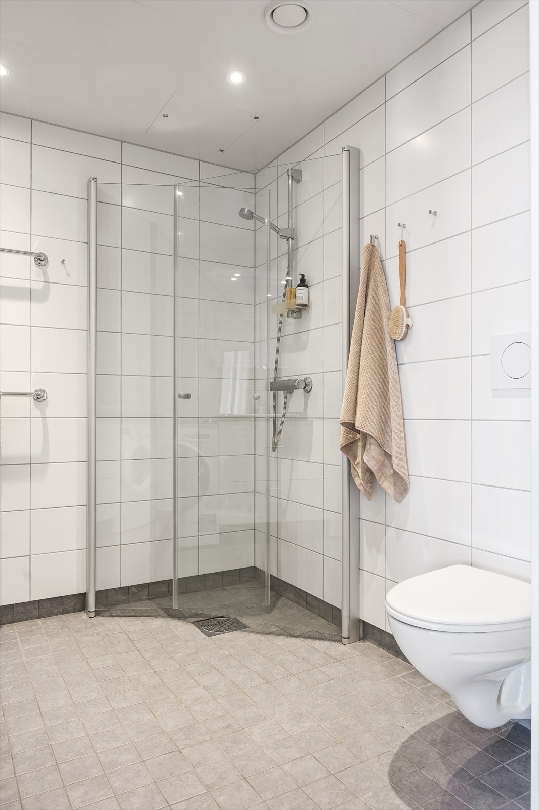 Videre består badet av dusjhjørne med innfellbare dører og vegghengt toalett med innebygd sisterne. Opplegg for vaskemaskin og tørketrommel. Galleribilde