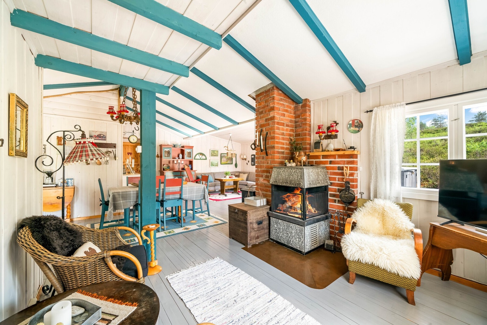 Lys og åpen stue med peisovn og vedovn på andre siden av teglsteinpipen. Galleribilde
