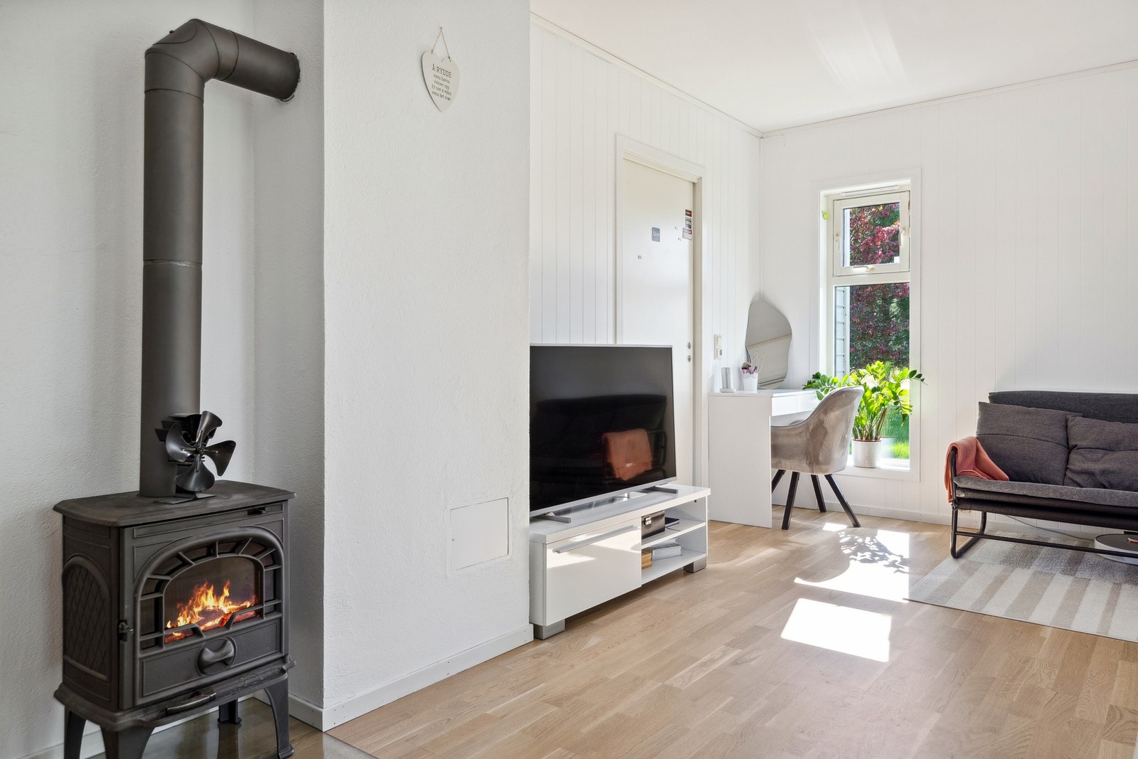 Allrommet har hvitmalt panel på veggene og gyllen, trestavs parkett på gulvet. Galleribilde