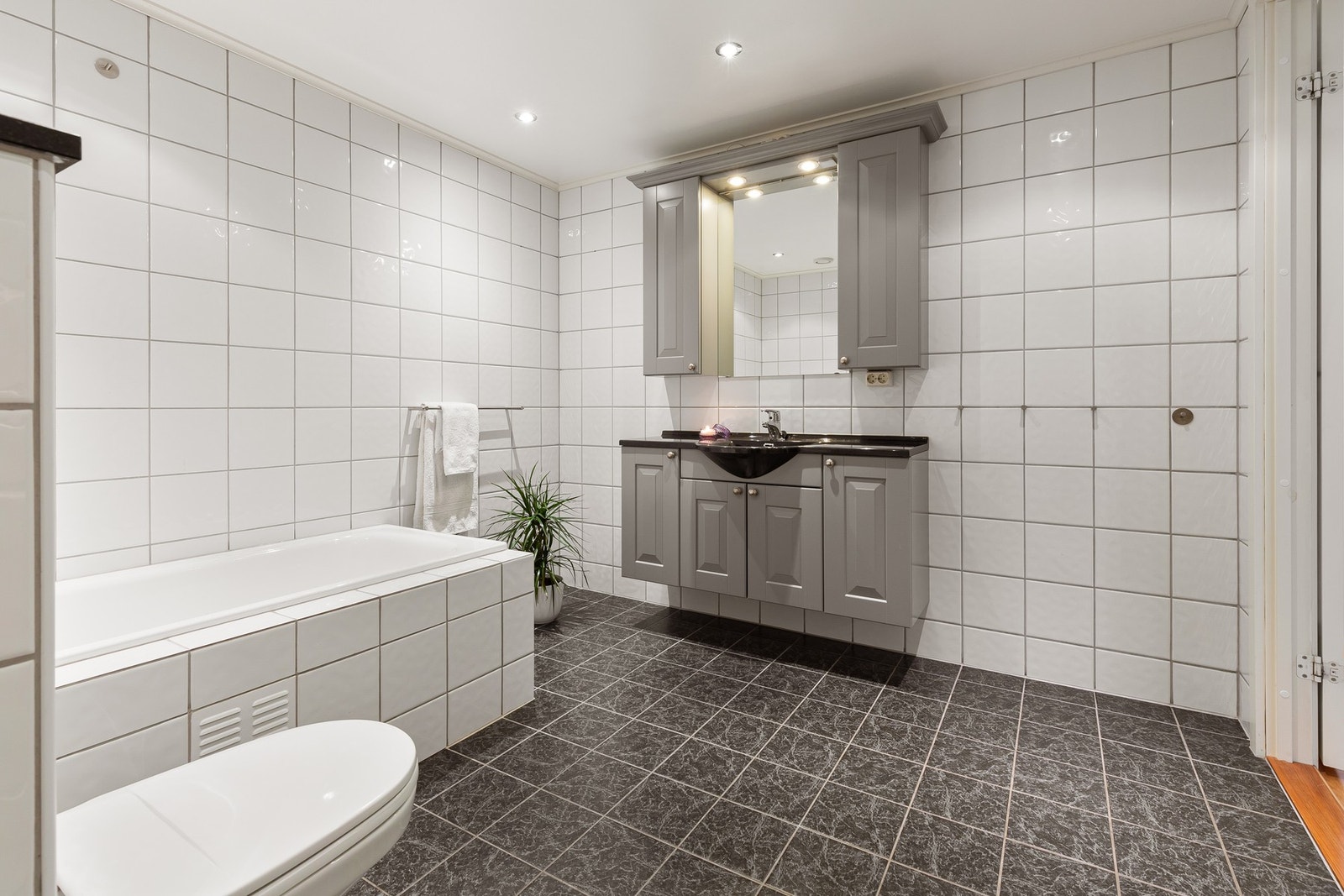 Badet er innredet med servant med speil, over- og underskap, vegghengt toalett og badekar. Galleribilde