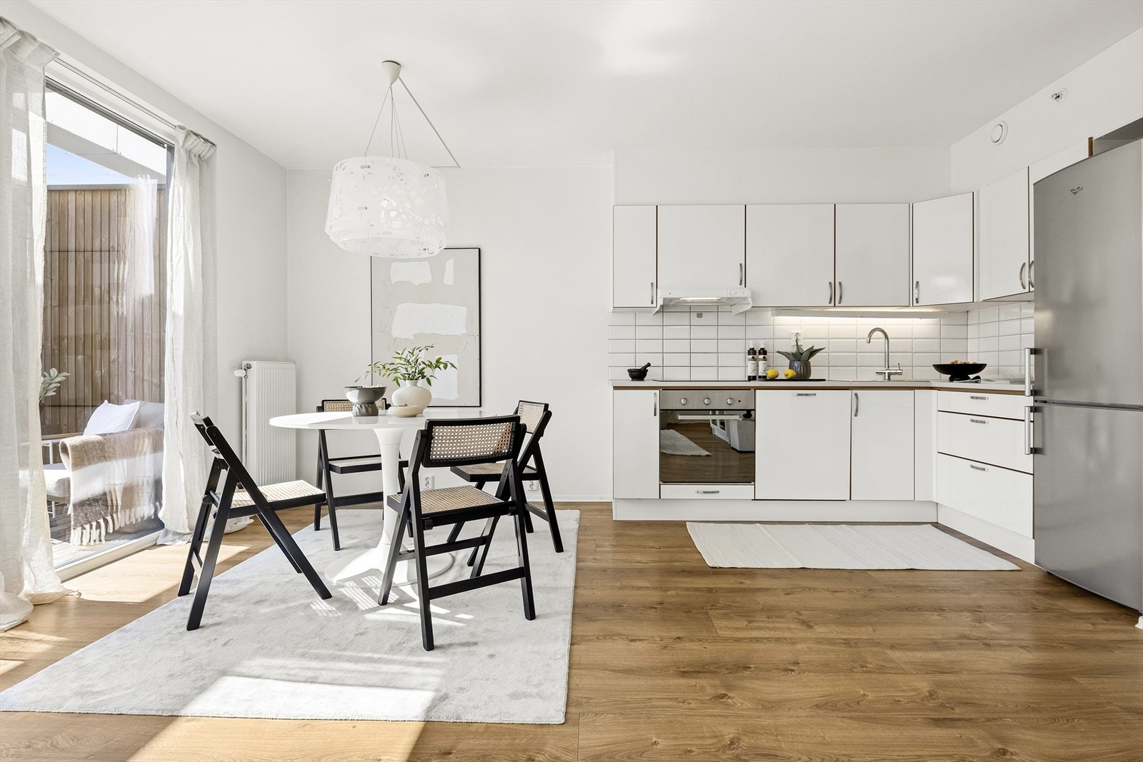 Lyst kjøkken med lys under overskap, fliser på vegg og integrerte hvitevarer. Galleribilde